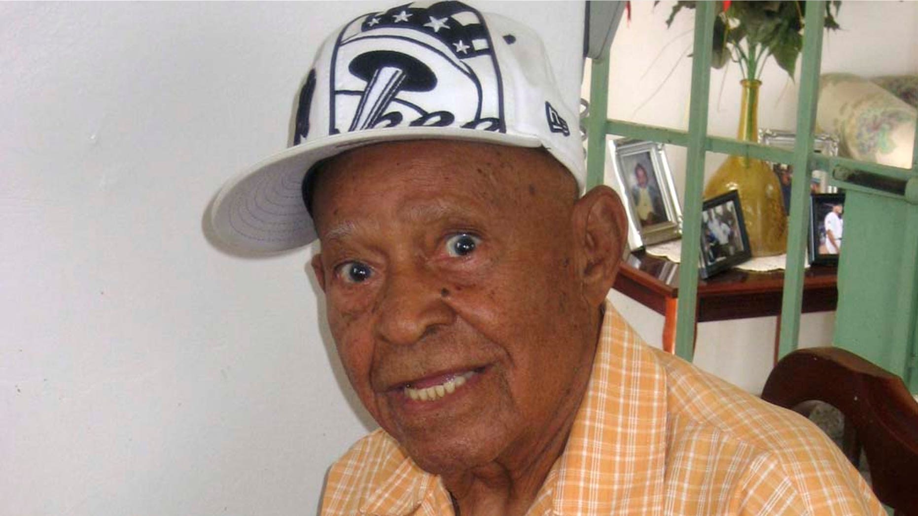 Una foto de archivo del 29 de julio de 2010 muestra al ex pelotero puertorriqueño Emilio "Millito" Navarro a los 104 años mientras sostiene su tarjeta de jugador de béisbol en su hogar en Ponce, Puerto Rico. Navarro, considerado el ex pelotero profesional más anciano del mundo, falleció el sábado 30 de abril de 2011 en Ponce a los 105 años, dijo su familia en un comunicado. (Foto AP/Danica Coto, Archivo)