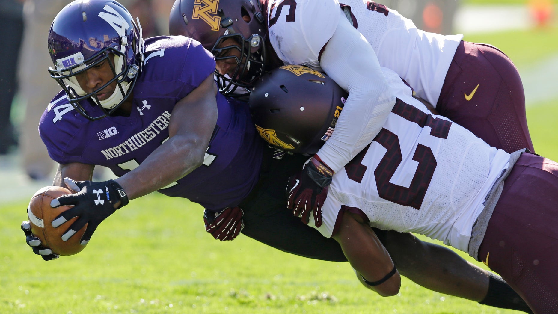 Minnesota defensive back Brock Vereen (21) and linebacker Aaron Hill (57) tackle Northwestern wide receiver Christian Jones (14) during the first half of an NCAA college football game in Evanston, Ill., Saturday, Oct. 19, 2013. (AP Photo/Nam Y. Huh)