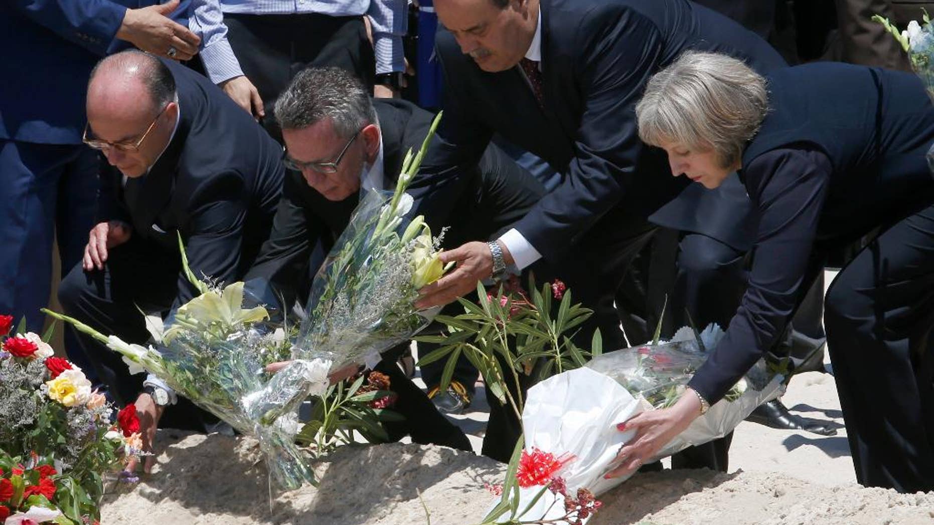 From right to left British Home Secretary Theresa May, Tunisian Interior Minister Mohamed Najem Gharsalli, , German Interior Minister Thomas de Maiziere and French Interior Minister Bernard Cazeneuve lay flowers on the beach in front of the Imperial Marhaba hotel in the Mediterranean resort of Sousse for the tribute in Sousse, Tunisa, Monday, June 29, 2015. The top security officials of Britain, France, Germany and Belgium are paid homage to the people killed in the terrorist attack in Sousse on Friday. (AP Photo/Abdeljalil Bounhar)