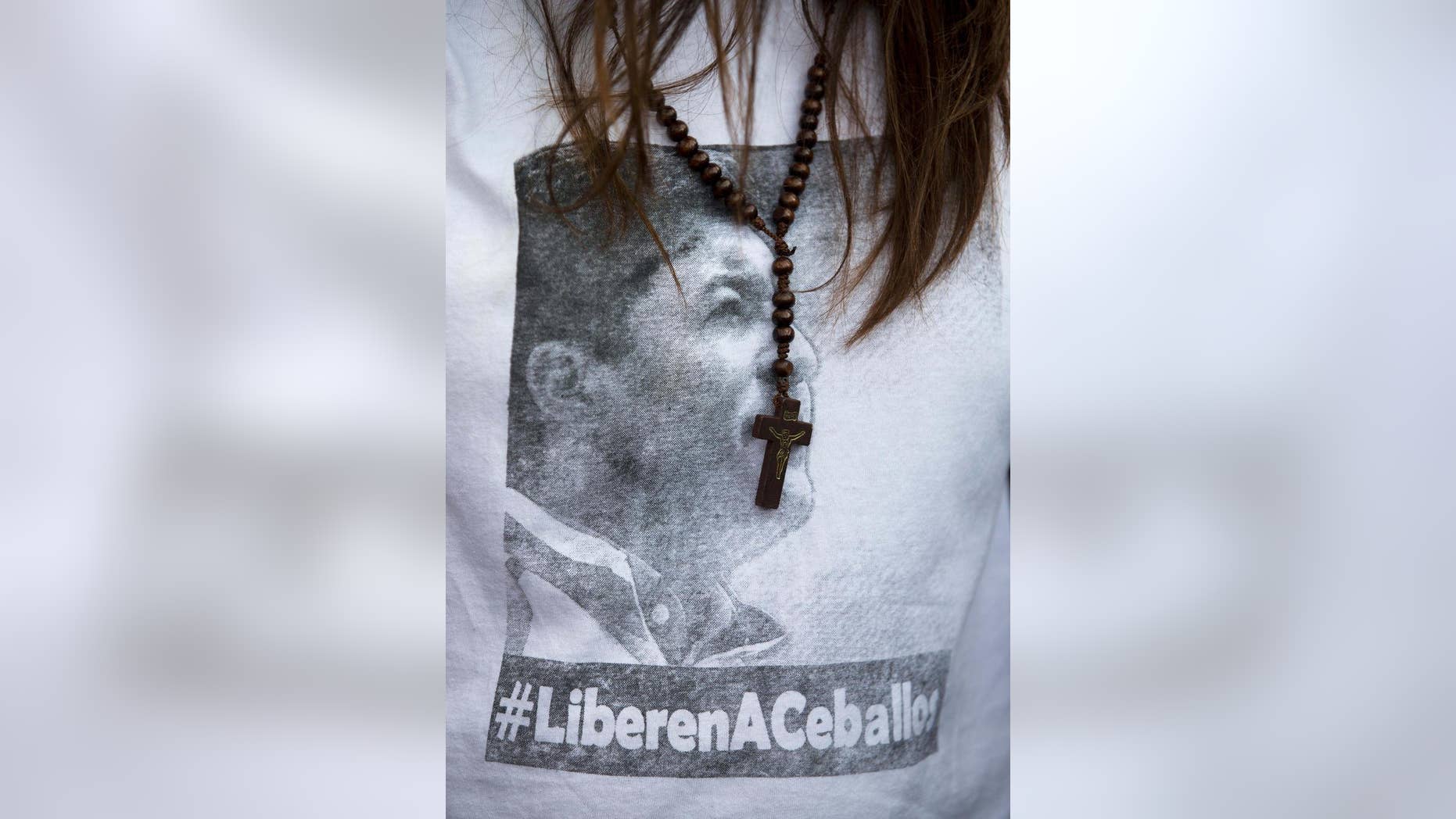 FILE - In this Friday, Jan. 23, 2015, file photo, San Cristobal's Mayor Patricia Gutierrez wears a rosary and a T-shirt with an image of her jailed husband Daniel Ceballos with a hashtag that reads in Spanish "Free Ceballos" at a protest in San Cristobal, Venezuela. Ceballos who was striking with fellow jailed leader Leopoldo Lopez to demand that the government set a date for parliamentary elections and release jailed politicians like themselves, has called off his hunger strike after 20 days. His attorney Juan Carlos Gutierrez said Thursday, June 11, that Ceballos’ demands had been partially met. (AP Photo/Fernando Llano, File)