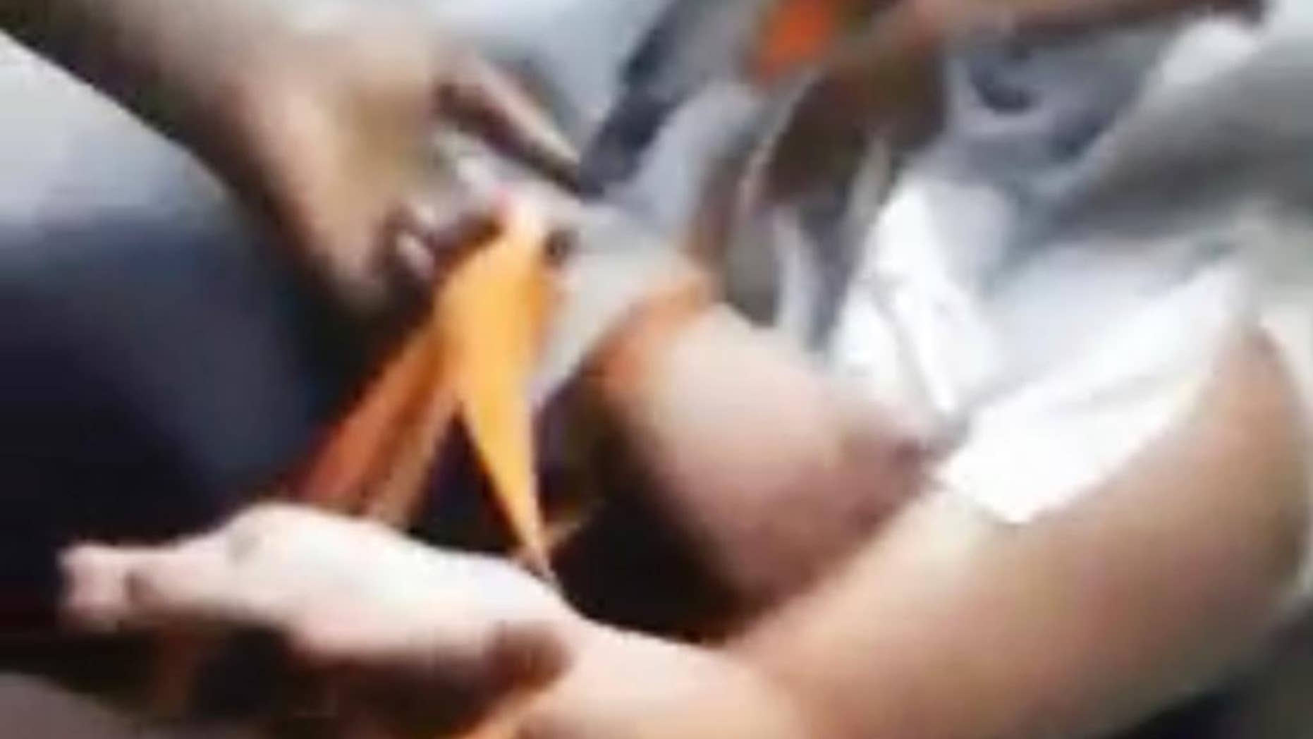This image from a video that was broadcast live on Facebook and later posted on Vidme shows a frame in which a man, right, is assaulted in Chicago. The video shows the man with his mouth taped shut as a woman and other people cut off his shirt and hair with a knife, and someone pushes his head with his or her foot. Chicago Police Superintendent Eddie Johnson said Wednesday, Jan. 4, 2017, that the victim has mental health challenges, and he called the video "sickening." (Vidme via AP)