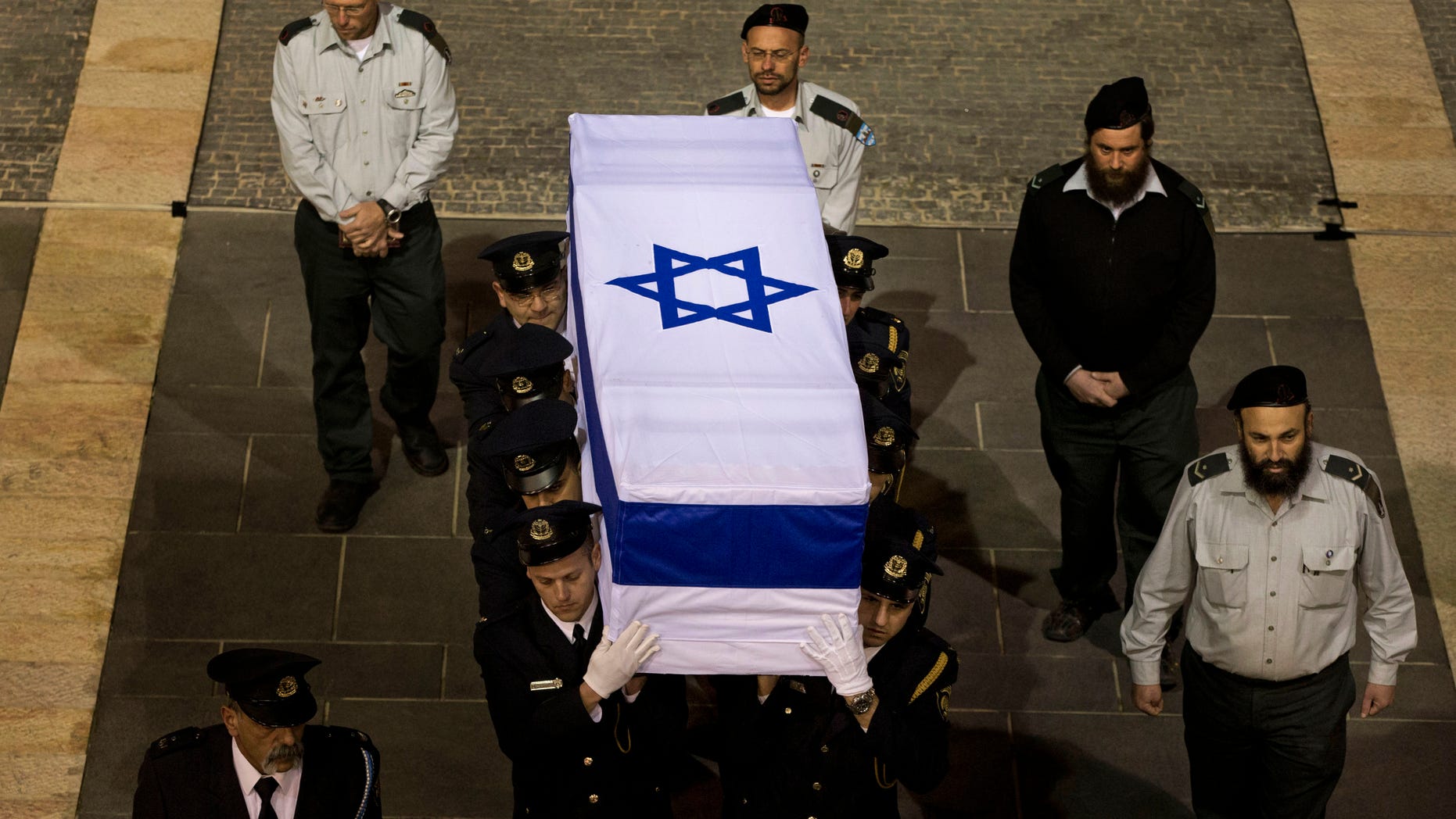 Members of the Knesset guard carry the coffin of late Israeli Prime Minister Ariel Sharon at the Knesset plaza, in Jerusalem, Sunday, Jan. 12, 2014. Israelis from all walks of life flocked to parliament Sunday to catch a glimpse of Ariel Sharon's coffin and pay their final respects to the iconic former prime minister and general. The 85-year-old Sharon died Saturday eight years after a devastating stroke left him in a coma. (AP Photo/Bernat Armangue)