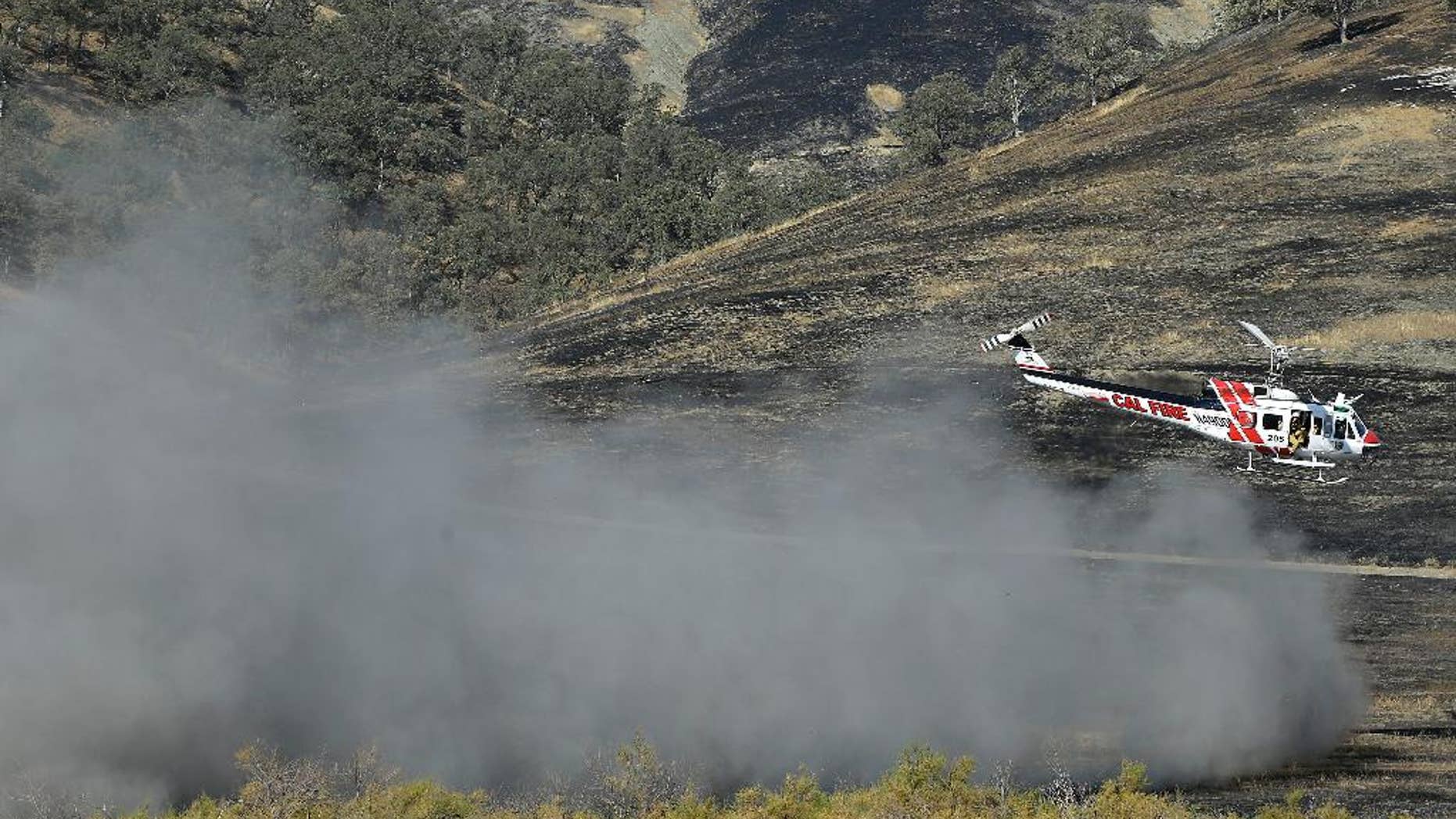 A Cal Fire helicopter flies over the Bear Creek portion of Cache Creek near Clearlake, Calif., Thursday, Aug. 6, 2015. Crews backed by important firefighting resources are gaining ground against a massive Northern California wildfire, but it may be several days before thousands of evacuees can return home, officials said Thursday. (AP Photo/Jeff Chiu)