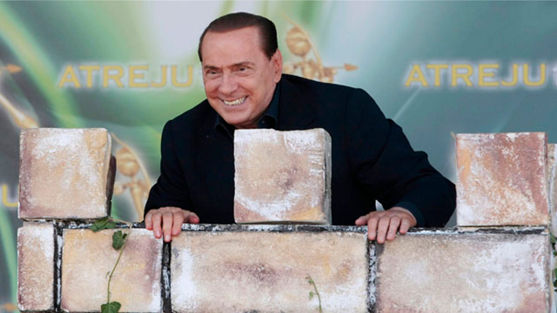 September 12: Italian Premier Silvio Berlusconi leans against a mock tower during a People of Freedom party meeting in Rome. (AP)