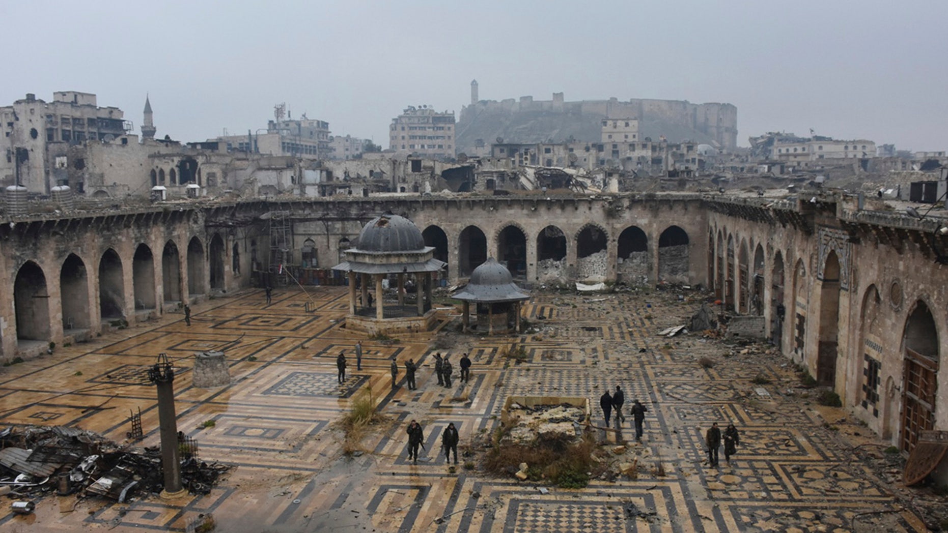 This photo released by the Syrian official news agency SANA, shows Syrian troops and pro-government gunmen marching walk inside the destroyed Grand Umayyad mosque in the old city of Aleppo, Syria, Tuesday, Dec. 13, 2016.