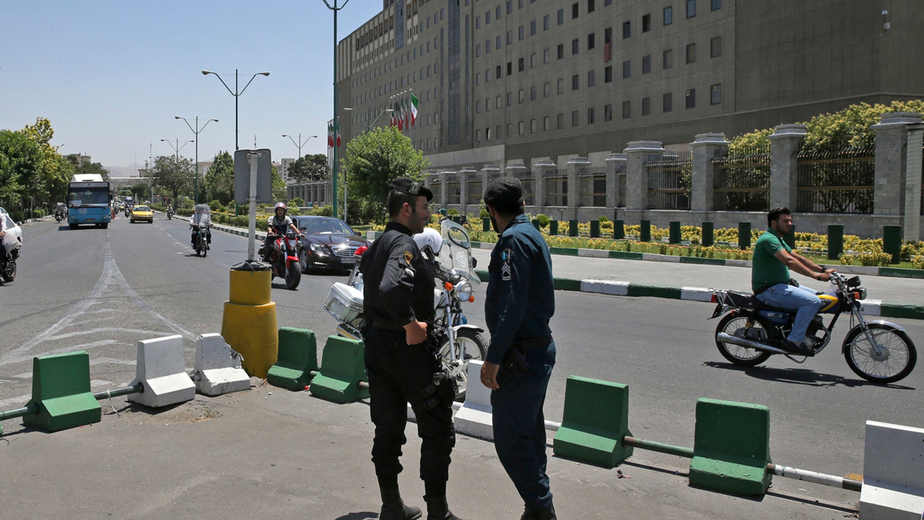 Police officers stand guard as vehicles drive past Iran's parliament building in Tehran, Iran, Thursday, May 8, 2017.