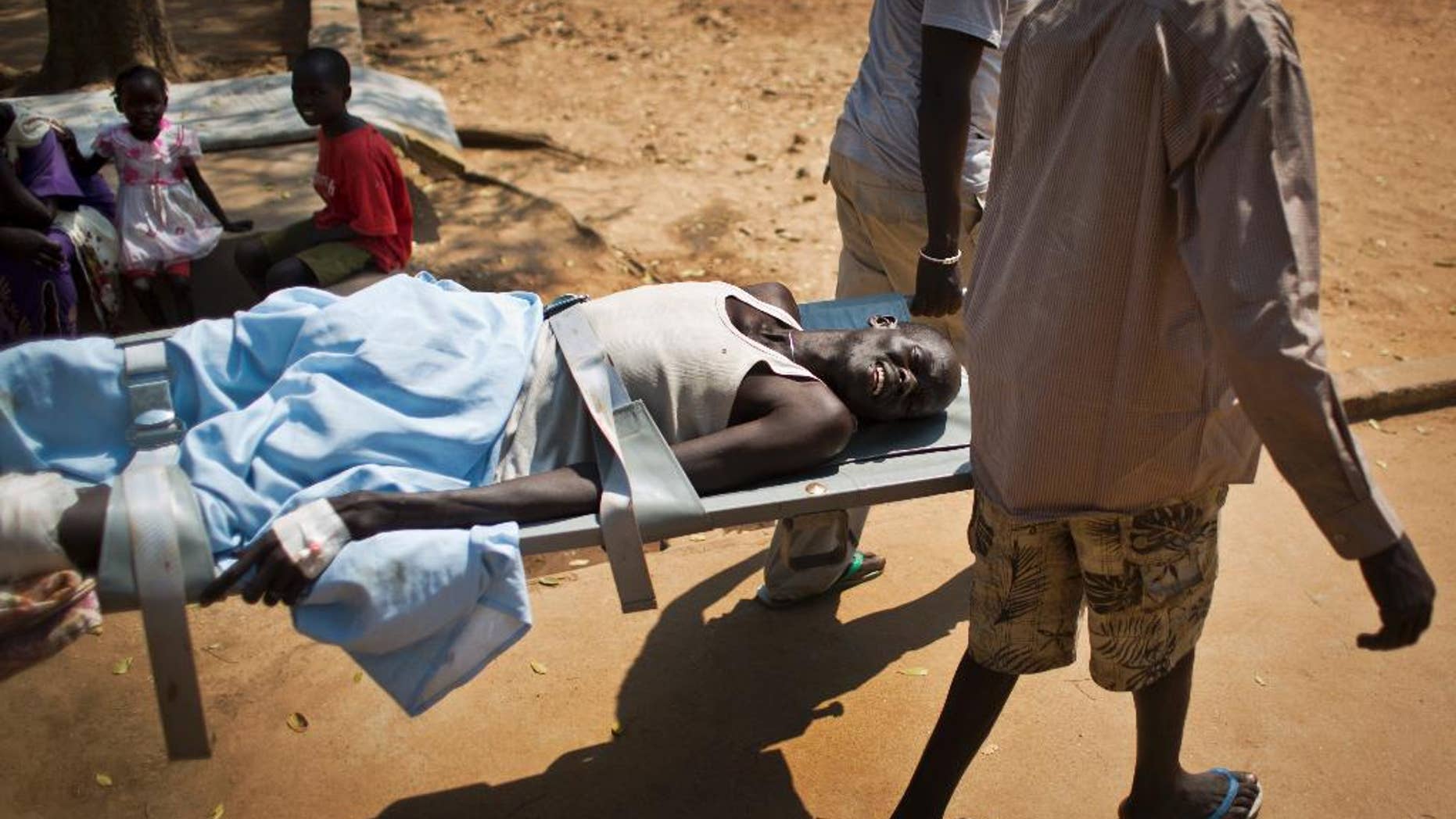FILE In this Saturday Dec. 28 2013 file photo, a man with a gunshot wound in his leg is carried by stretcher from one ward to another inside the Juba Military Hospital in Juba, South Sudan. One year after mass violence broke out in South Sudan, battles between government forces and rebel fighters continue, and aid officials say the international community must help residents stave off mass hunger. (AP Photo/Ben Curtis, File)