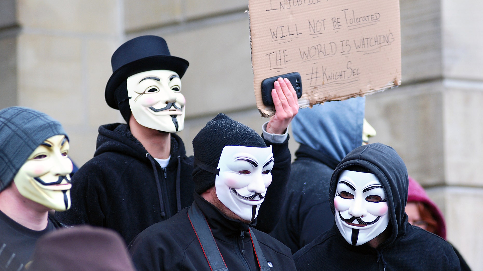 Members of the group Anonymous, wearing Guy Fawkes masks, protest alleged cover-up in the case of two eastern Ohio high school football players charged with raping a 16-year-old girl. (AP Photo/Herald-Star, Michael D. McElwain)
