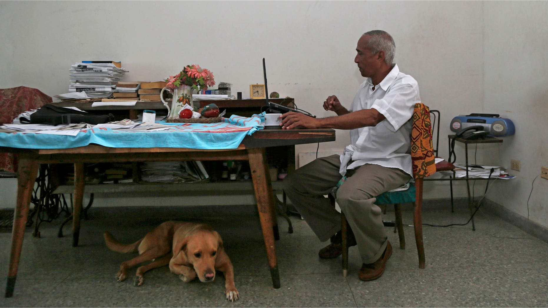 In this Thursday, April 16, 2015 photo, Cuban dissident Hildebrando Chaviano works at his laptop inside his home in Havana, Cuba. Chaviano, a government lawyer turned independent journalist, is one of at least two Cuban dissidents who made it past a first round of voting to become candidates in Sunday's local elections. (AP Photo/Desmond Boylan)