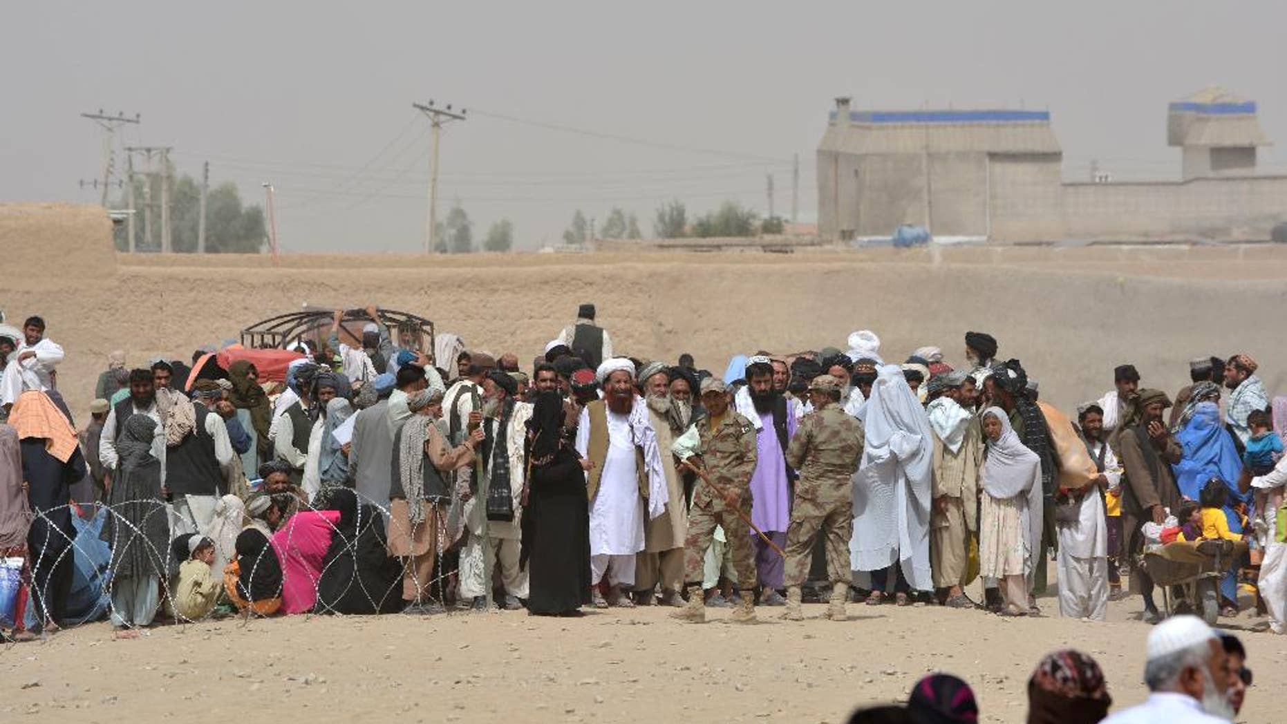 People en route to Afghanistan wait at the Pakistani border post, Chaman, Wednesday, Aug. 31, 2016. Border crossing in Chaman in southwest Pakistan is closed for 15th consecutive day after Afghan protesters burned a Pakistani flag on the other side of the border. Border will reopen on Thursday morning after negotiations between Pak and Afghan officials, official said. (AP Photo/Matiullah Achakzai)