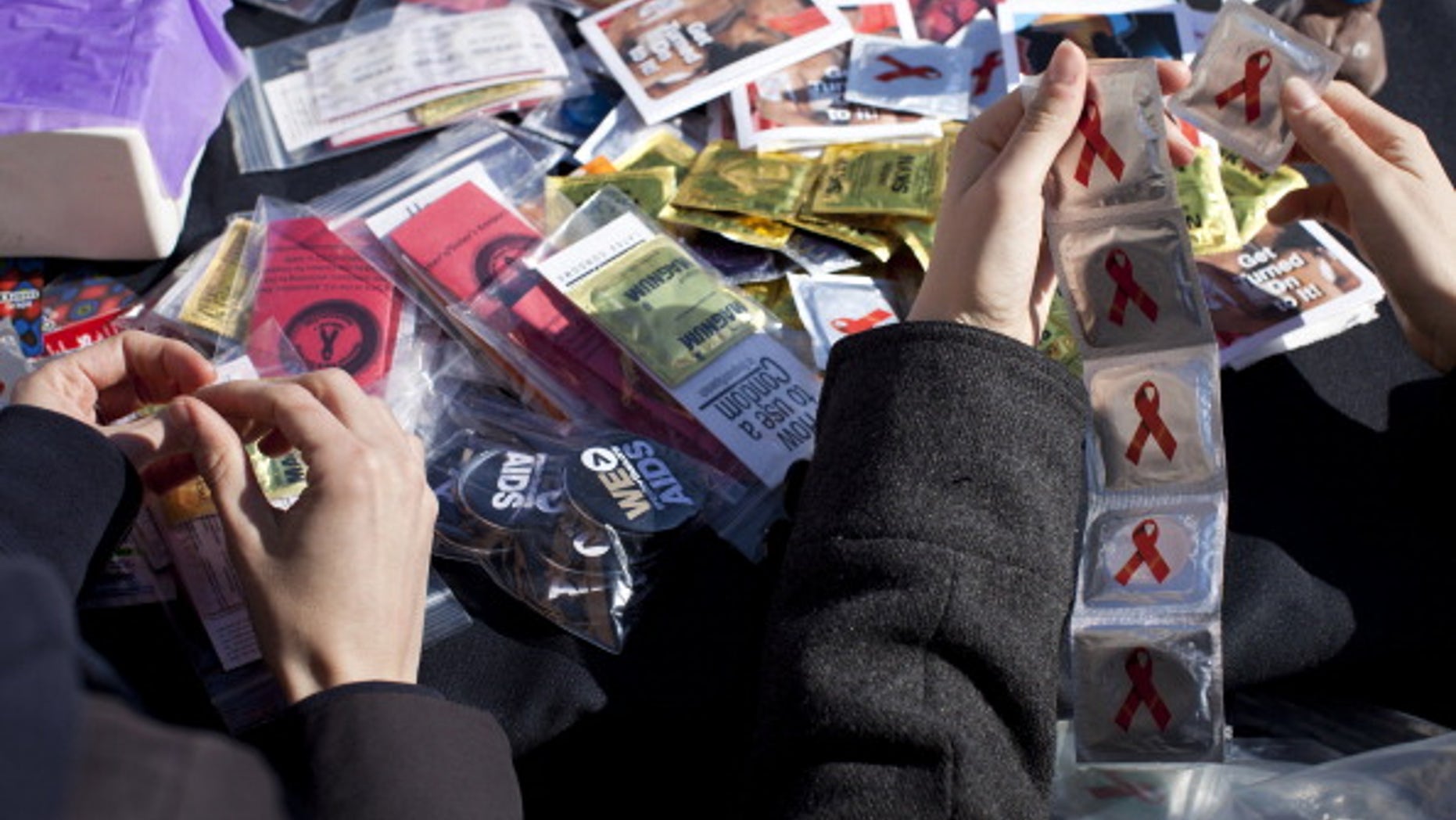 Volunteers separate condoms to give away during a free HIV testing event .