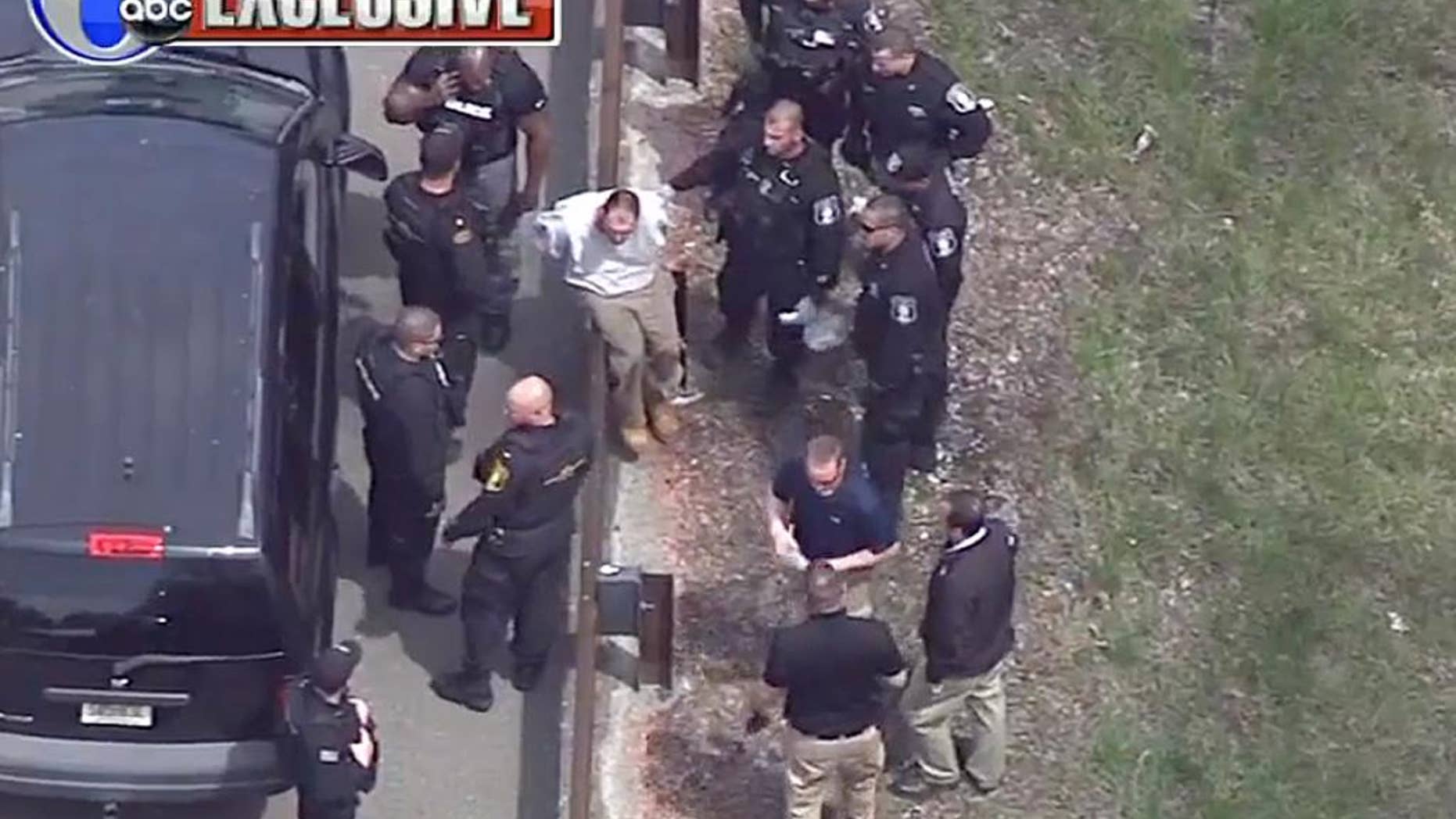 In this frame grab taken from video, Arthur Buckel, center, sits on a guardrail surrounded by police officers after being taken into custody near Double Trouble State Park, Monday, May 9, 2016, in Lacey Township, N.J. The minimum security prison inmate who escaped last week once served time for manslaughter for killing a baby and had been behind bars on assault, drug possession and burglary charges. (AP Photo/ WPVI-TV)