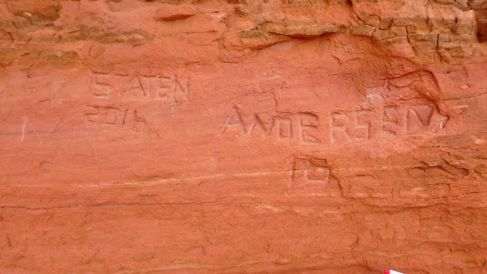 In this April 15, 2016, photo, released by the National Park Service shows carved graffiti at Frame Arch at Arches National Park. Officials at Utah's Arches National Park are investigating large graffiti so deeply carved into one of the park's famous red rock arches that it might be impossible to erase. (Alice deAnguera/National Park Service via AP)