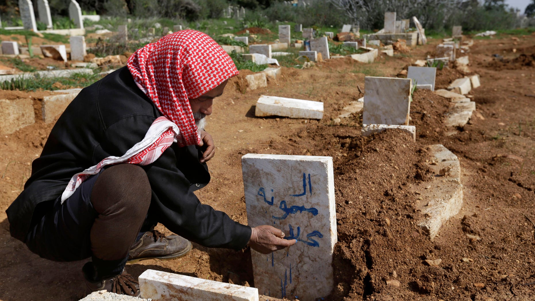 Feb. 24, 2013: A Syrian villager, Abu Ibrahim, 73, writes the name of his granddaughter on her grave who was killed from an airstrike by Syrian government forces, at Jabal al-Zaweya village of Sarja, in Idlib, Syria.
