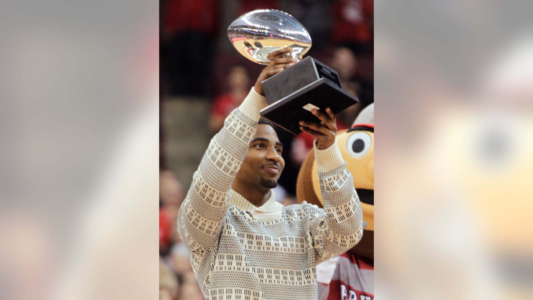 Ohio State quarterback Braxton Miller raises the Silver Football, awarded by the Chicago Tribune to the best football player in the Big 10, during a timeout in an NCAA college basketball game between Ohio State and Northwestern on Wednesday, Feb. 19, 2014, in Columbus, Ohio. (AP Photo/Jay LaPrete)