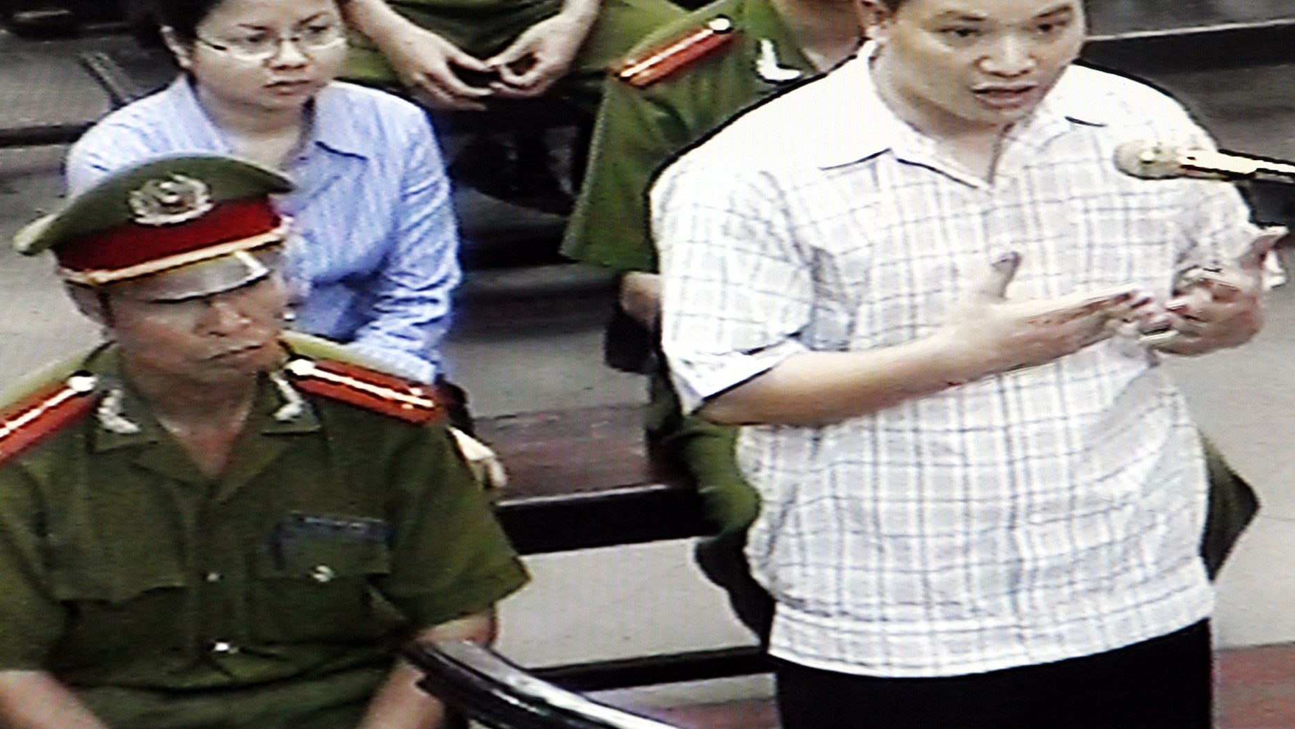 FILE - in this Friday, May 11, 2013 file photo, originally taken from TV footage, Nguyen Van Dai, right, testifies at a court as his fellow human rights activist Le Thi Cong Nhan, left in second row, listens during their trial in Hanoi, Vietnam. Deputy Secretary of State Dan Baer wanted to meet Nguyen Van Dai and Pham Hong Son, two dissidents well known to Western governments and rights organizations when he was in Vietnam. They have each served four-year prison terms in the past. They are under frequent surveillance and are often harassed, yet remain publicly committed to challenging the party, prepared to accept the risks to them and their family in doing so. (AP Photo)