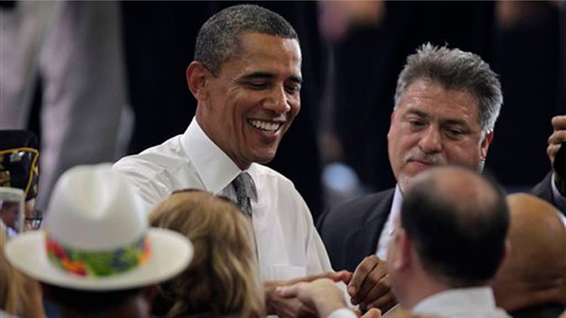 President Barack Obama shakes hands after speaking to a crowd gathered inside a hangar at the Muniz Air National Guard Base, shortly after his arrival in San Juan, Puerto Rico, Tuesday June 14, 2011. Obama's visit to Puerto Rico marks the first by a sitting U.S. President since John Kennedy. (AP Photo/Brennan Linsley)