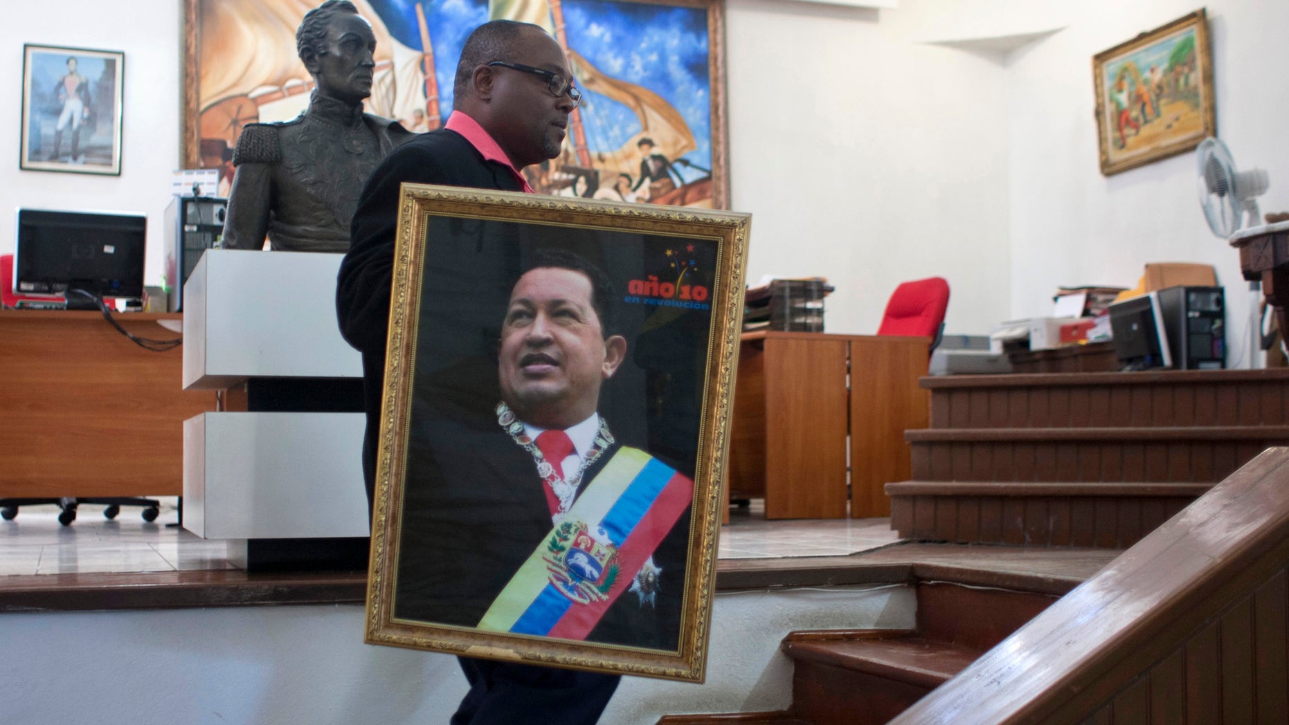 Pierre Denis, who works at Venezuela's embassy, carries an image of Venezuela's President Hugo Chavez after holding a Mass to pray for Chavez's health in Petion-Ville, Haiti, Friday, Dec. 21, 2012. Chavez is recovering in Cuba from surgery, his fourth operation related to pelvic cancer since June 2011. (AP Photo/ Photo/Dieu Nalio Chery)