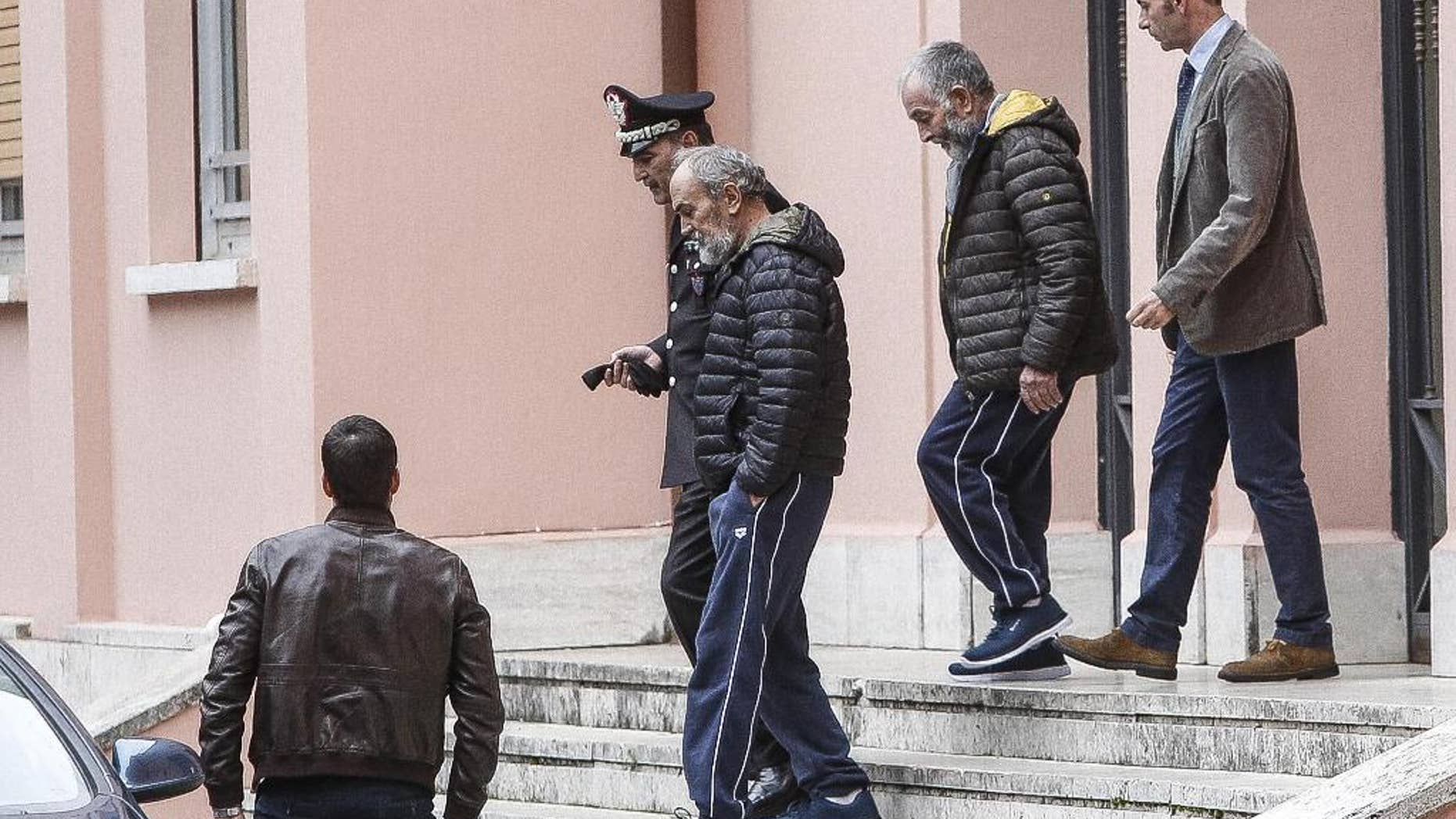 The two Italian hostages that were freed in Libya, Bruno Cacace, second from left, and Danilo Calonego, second from right, leave a police station after being questioned by prosecutor Sergio Colaiocco, in Rome, Saturday, Nov. 5, 2016. The two had been kidnapped at Gath, Libya, on Sept. 19. (Giuseppe Lami/ANSA via AP)