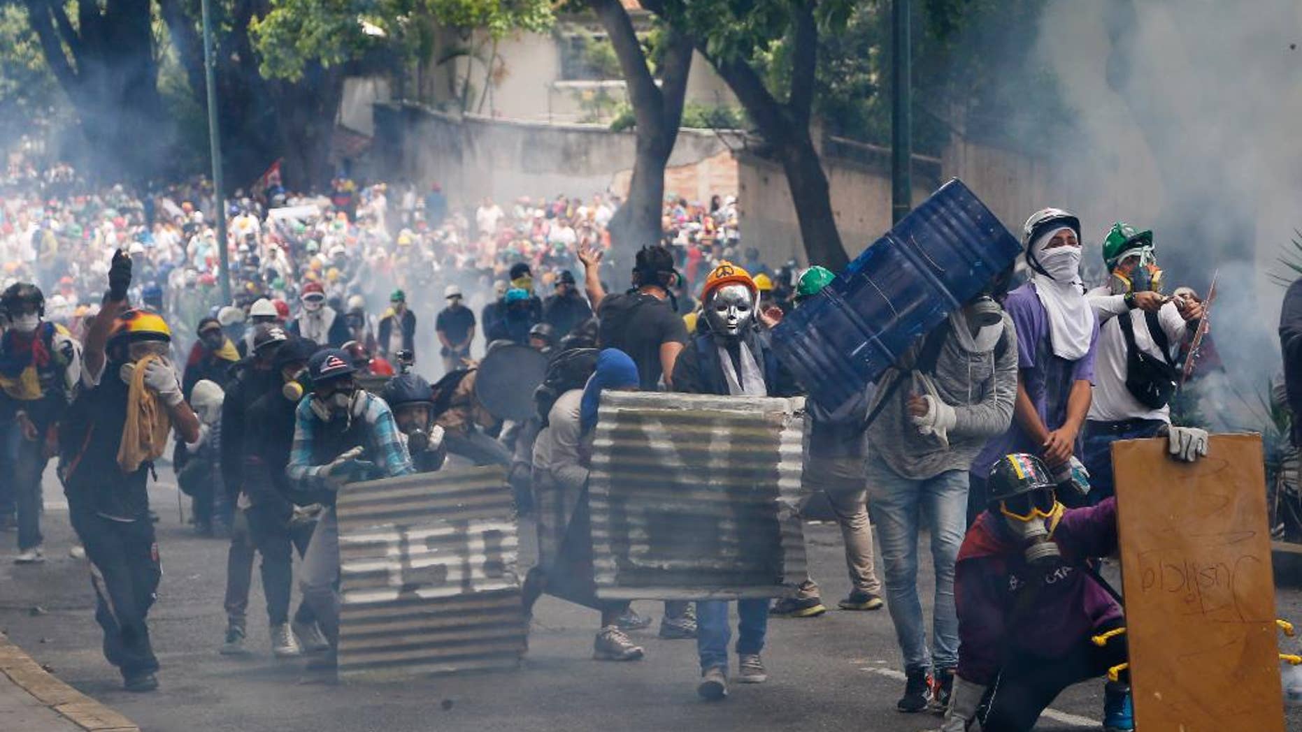 Masked and helmeted demonstrators face off with security forces during an opposition May Day march in Caracas, Venezuela, Monday, May 1, 2017. Venezuelans are taking to the streets in dueling anti- and pro-government May Day demonstrations as an intensifying protest movement enters its second month. (AP Photo/Ariana Cubillos)