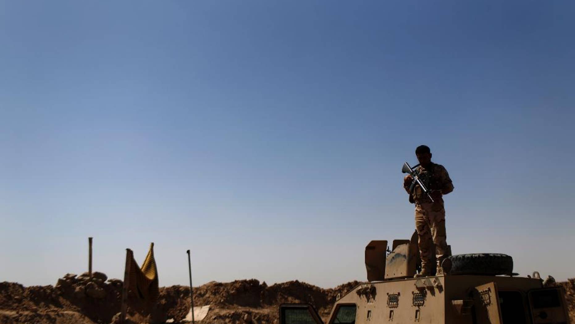 A Kurdish Peshmerga fighter stands guard atop an armored vehicle at a combat outpost on the outskirts of Makhmour, 300 kilometers (186 miles) north of Baghdad, Iraq, Saturday, Sept. 6, 2014. The U.S. and nine key allies agreed Friday, that the Islamic State group is a significant threat to NATO countries and that they will take on the militants by squeezing their financial resources and going after them with military might. (AP Photo/ Marko Drobnjakovic)