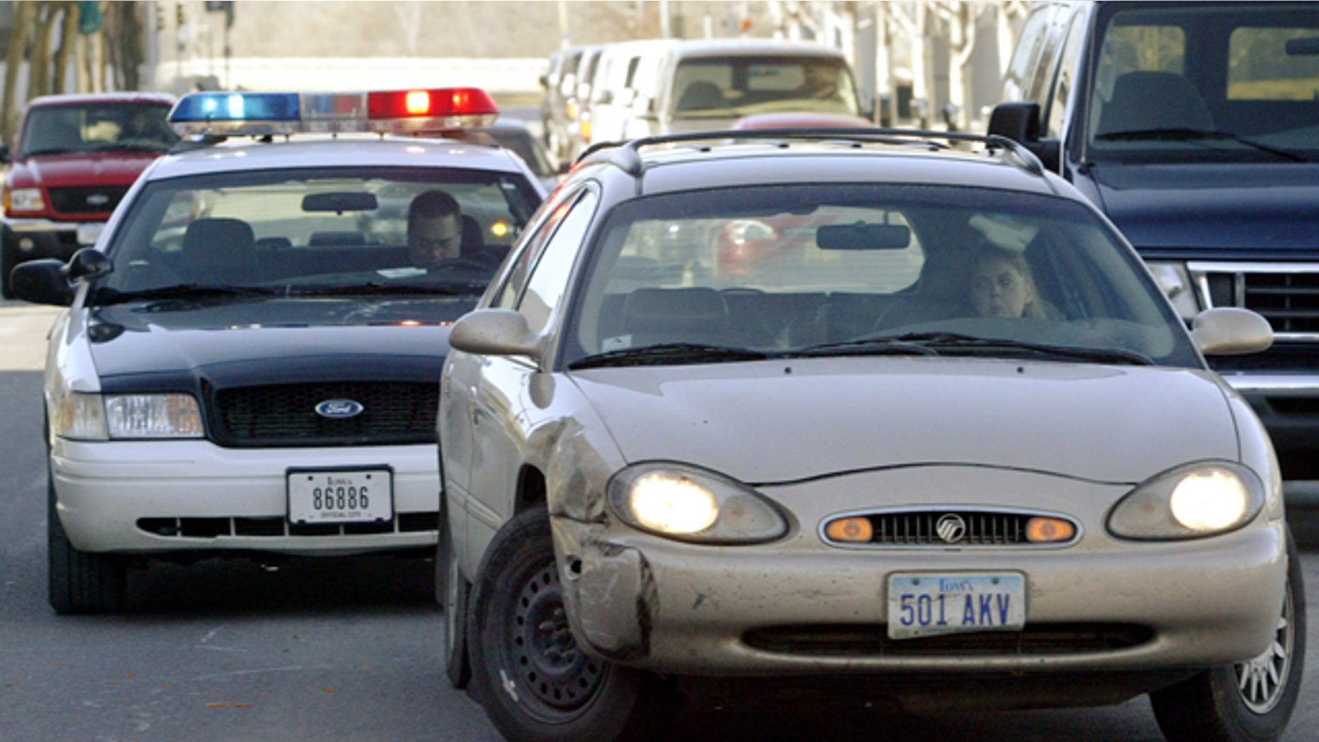 FILE: A motorist whose car has its two front wheels opposing each other is pulled over by a policeman for a moving traffic violation.