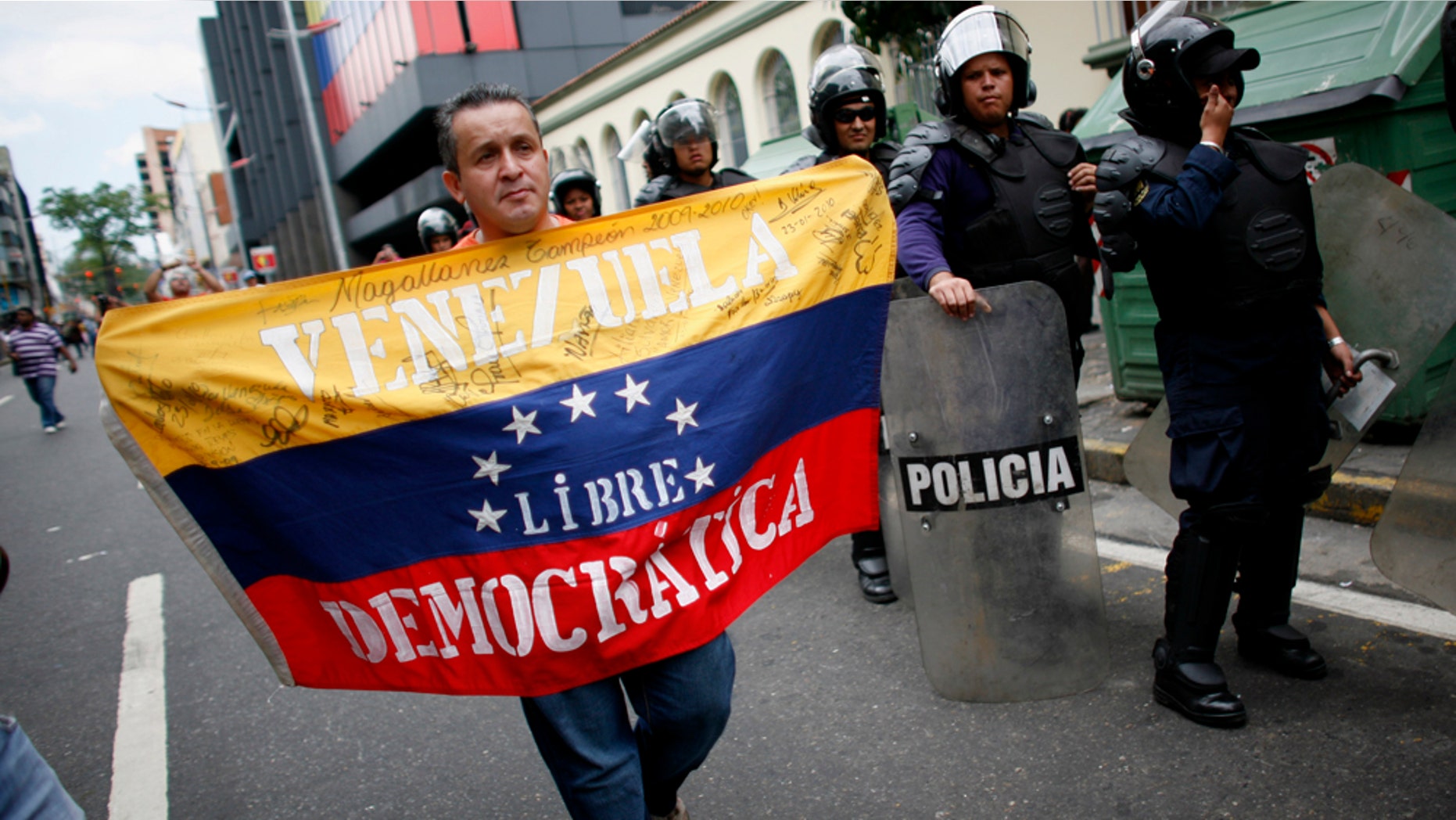 An opponent of Venezuelaâs President Hugo Chavez holds a Venezuelan flag that reads "Venezuela Free Democracy" on a street near the National Assembly in Caracas, Venezuela, Wednesday, Jan. 5, 2011. Opposition lawmakers gained a bigger presence and a platform to challenge President Hugo Chavez as a new National Assembly took office on Wednesday. They will have to contend with a president whose allies granted him expanded powers to pass laws by decree. (AP Photo/Ariana Cubillos)