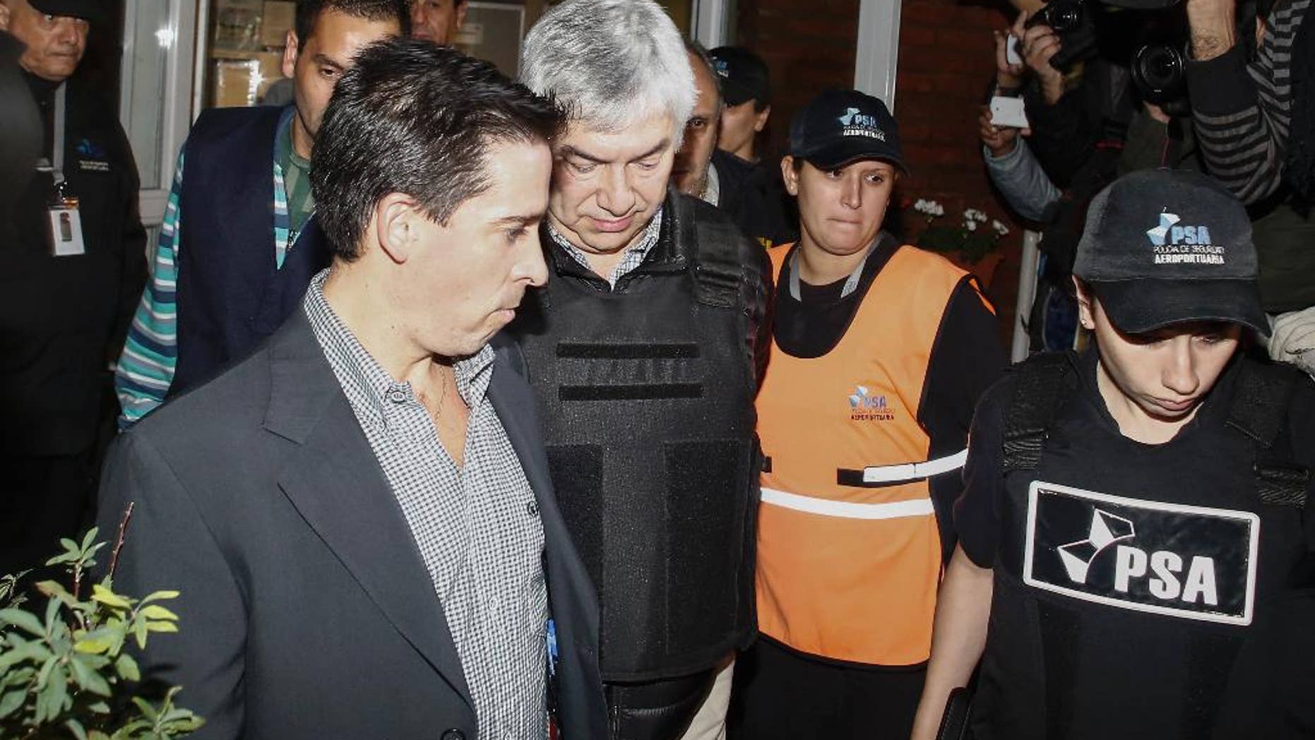 Argentine businessman Lazaro Baez, center, is escorted by police after being arrested as part of an investigation into alleged money laundering, at an airport on the outskirts of Buenos Aires, Argentina, late Tuesday, April 5, 2016. Baez, who got large public works contracts during the Kirchner and Fernandez administrations, is accused of embezzling and laundering millions. He denies any wrongdoing. (AP Photo/Agustin Marcarian)