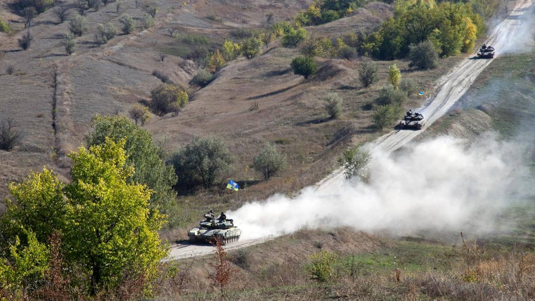 Ukrainian army tanks roll from the front line near the village of Krymske, Luhansk region, Eastern Ukraine, Monday, Oct. 5, 2015. A summit reviving a European push to bring peace to eastern Ukraine ended Friday with a call for the delay of contentious rebel plans to hold local elections this month and for both sides to begin a promised withdrawal of smaller-caliber weapons. (AP Photo/Inna Varenytsia)