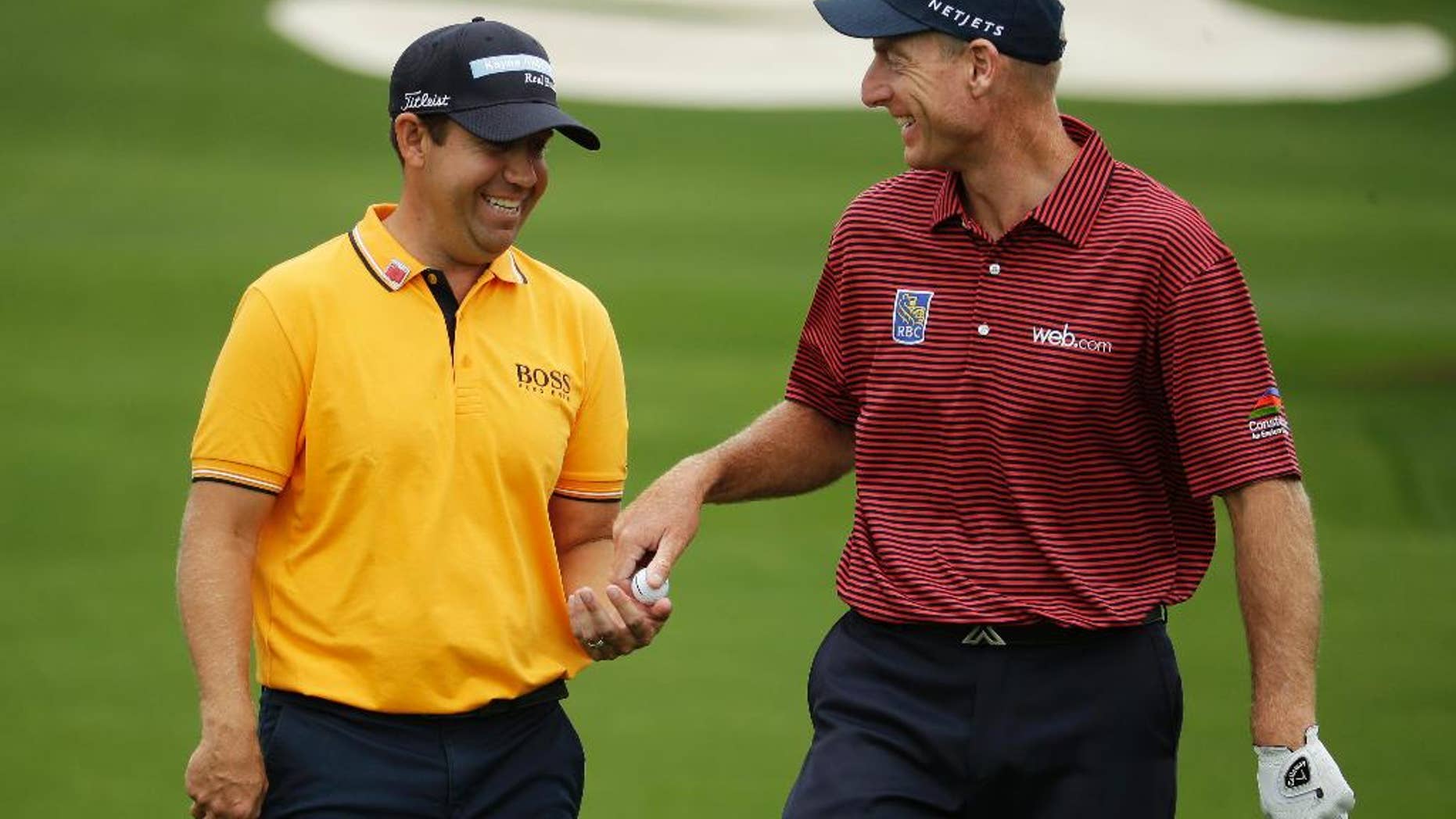 Jim Furyk, right, gives Erik Compton a ball before teeing off at the eighth hole during a practice round for the Masters golf tournament Monday, April 6, 2015, in Augusta, Ga. (AP Photo/Charlie Riedel)