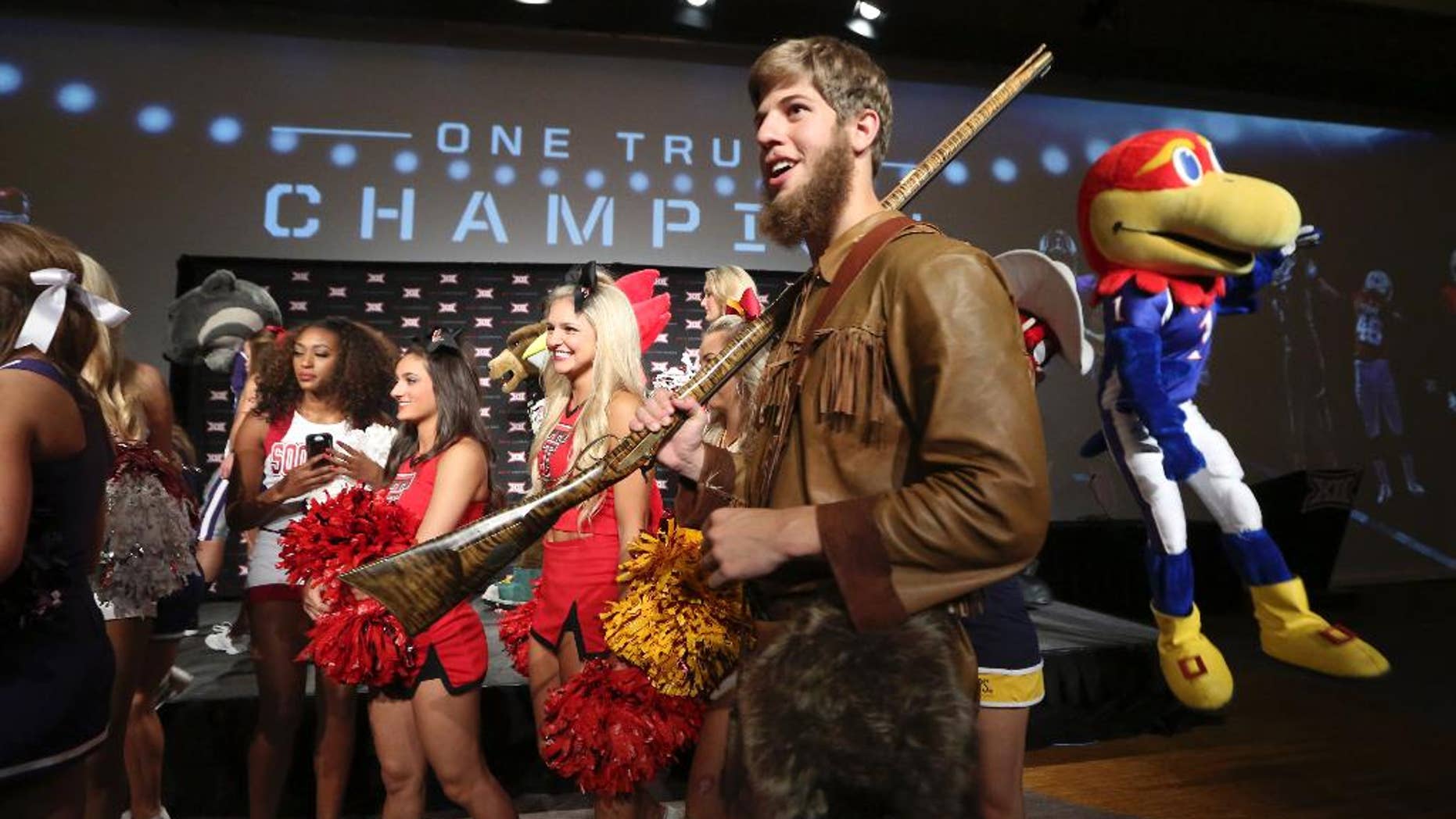 Michael Garcia, dressed as West Virginia's mountaineer mascot, caries a musket after posing for a photo with cheerleaders and mascots at the Big 12 Conference NCAA college football media days in Dallas, Tuesday, July 22, 2014. (AP Photo)