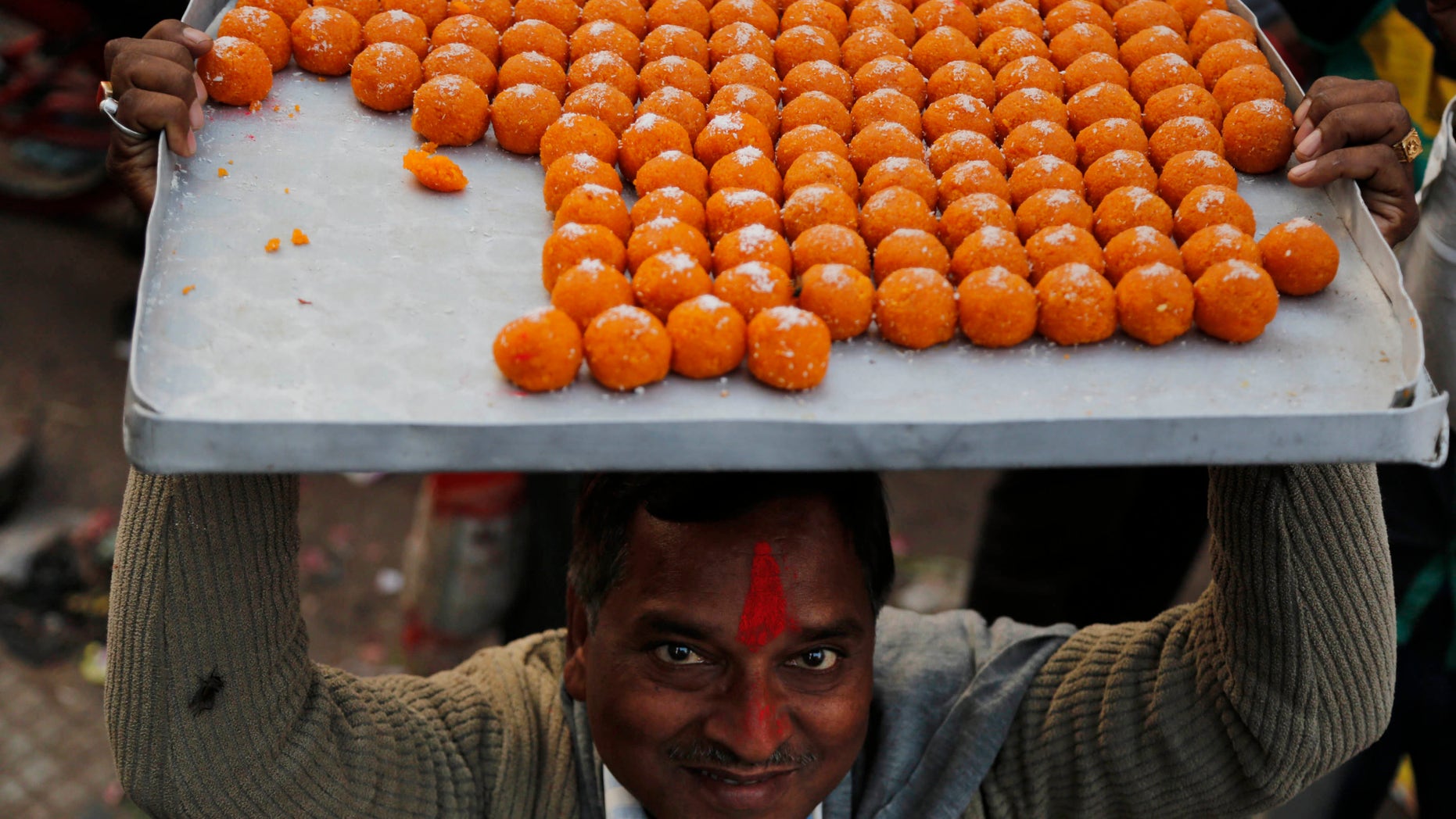 A man carries sweets to distribute as India’s main opposition Bharatiya Janata Party (BJP) supporters celebrate the party’s victory in various state Assembly elections in Allahabad,India , Sunday, Dec. 8, 2013. BJP, the main Hindu nationalist party, appeared to make strong political gains in four heartland states Sunday, as preliminary results showed the ruling Congress party sidelined in a race seen as a test before next year's general election. (AP Photo/Rajesh Kumar Singh)