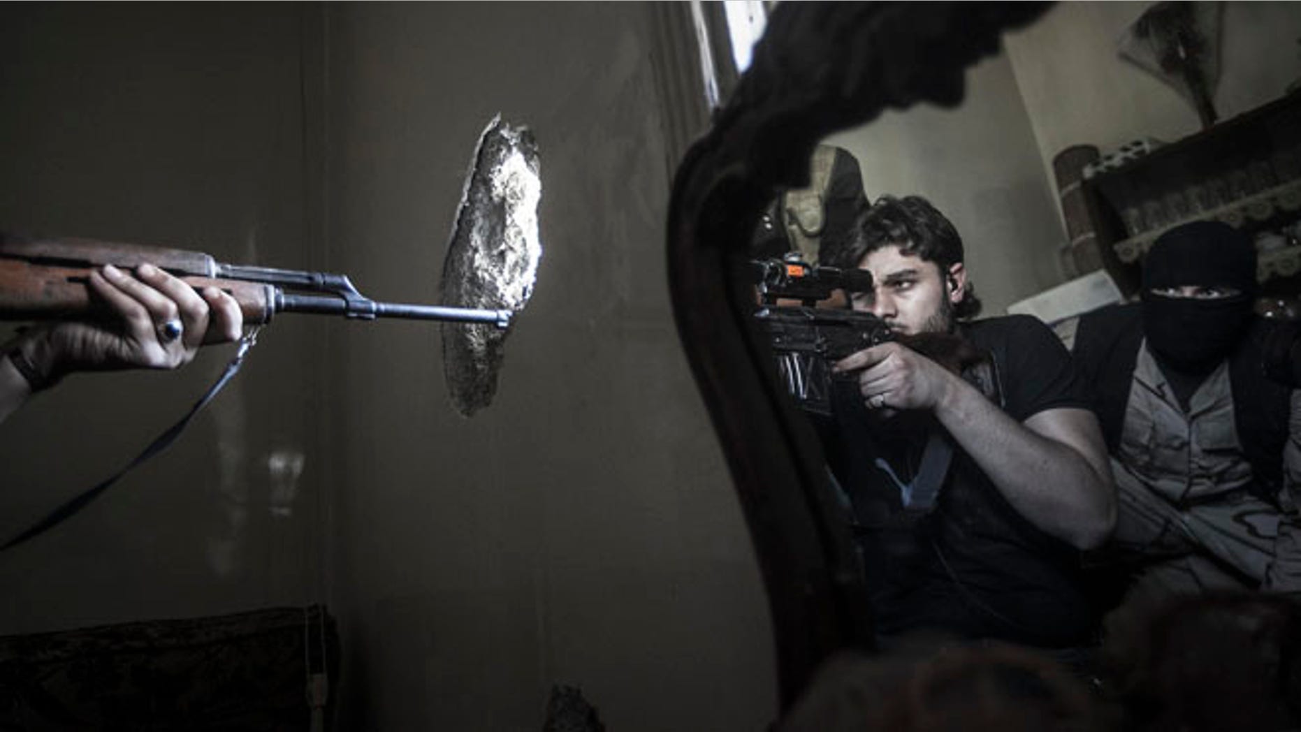 FILE 2012: A rebel sniper aims at a Syrian army position, seen with another rebel fighter reflected in a mirror, in a residential building in the Jedida district of Aleppo, Syria.