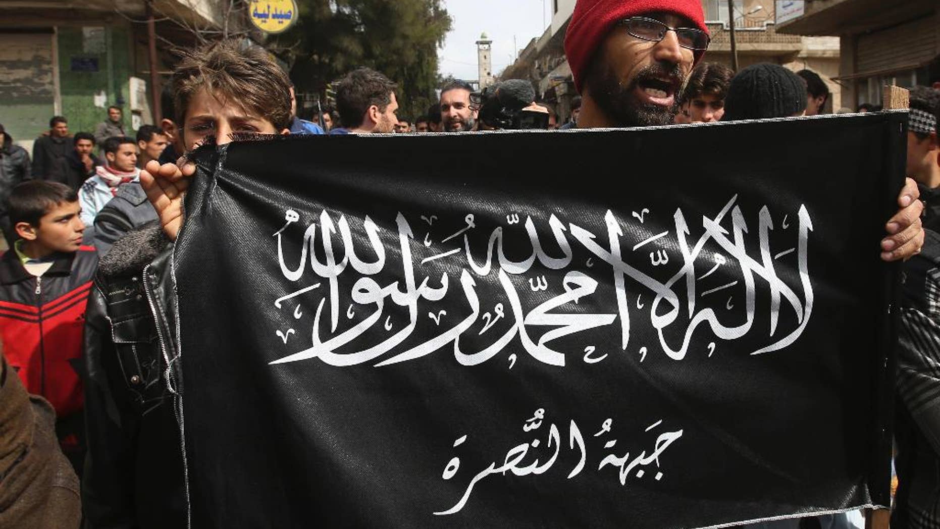 FILE- In this March 1, 2013 file photo, anti-Syrian President Bashar Assad protesters hold the Jabhat al-Nusra flag, as they shout slogans during a demonstration, at Kafranbel town, in Idlib province, northern Syria.
