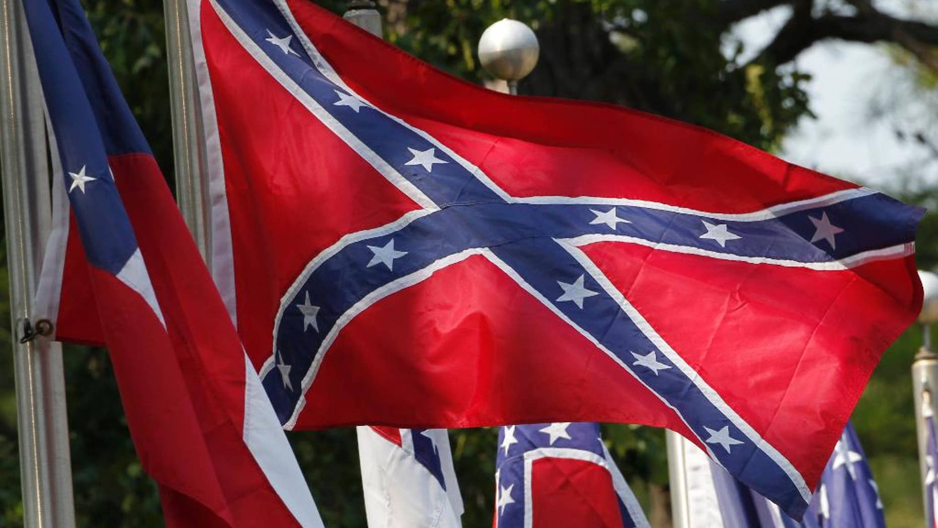 FILE - In this July 19, 2011 file photo, Confederate battle flags fly in Mountain Creek, Ala. The House has voted to ban the display of the Confederate flag on flagpoles at Veterans Administration cemeteries. The 265-159 vote would block descendants and others seeking to commemorate veterans of the Confederate States of America from flying the Confederate Battle Flag over mass graves, even on days that flag displays are permitted. (AP Photo/Dave Martin, File)