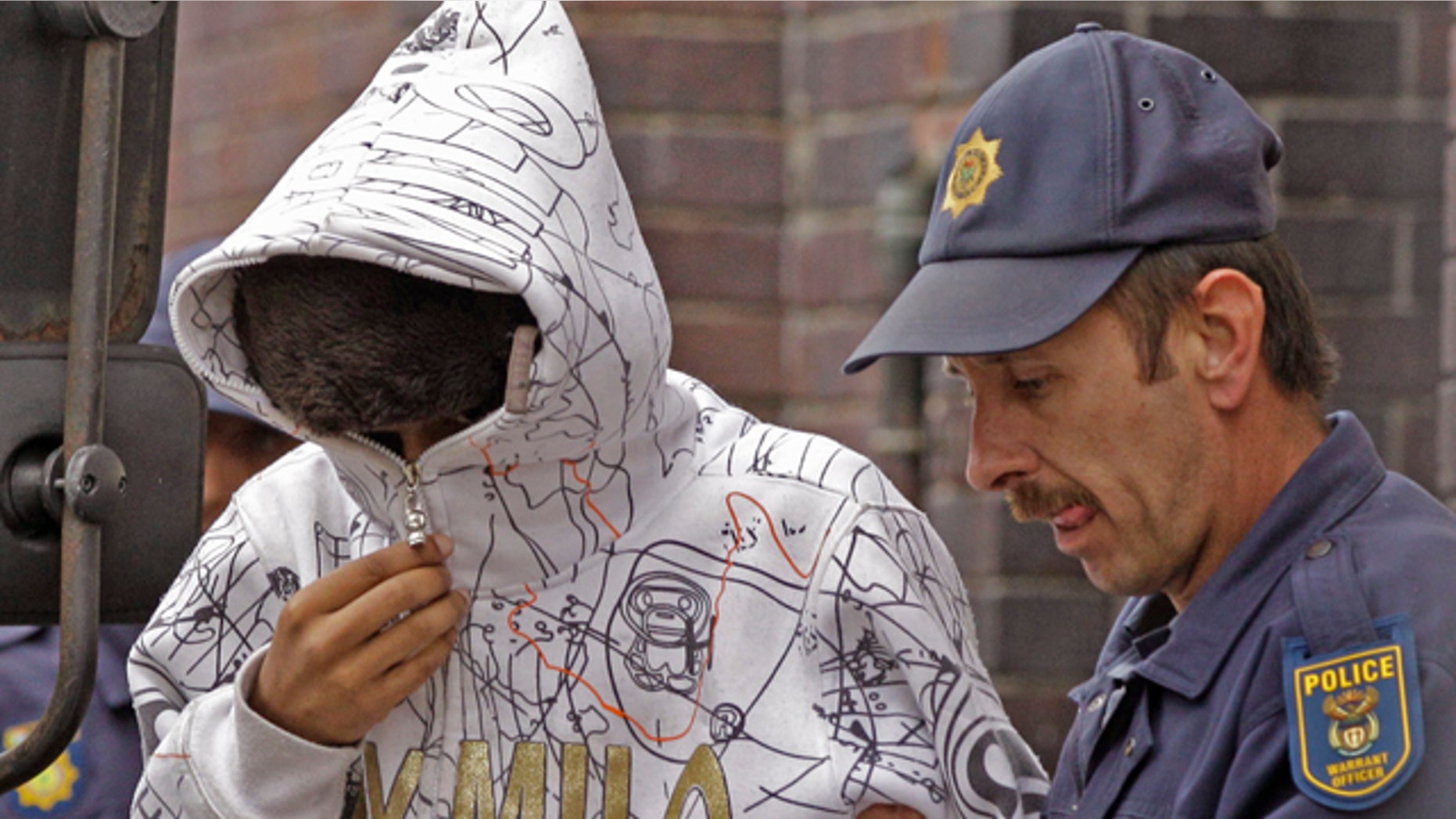 South African Xolile Mngeni, left, accused of taking part in the shooting death of Swedish Anni Dewani is led out of the court building by a police man at Cape Town, South Africa, Tuesday, Sept 20, 2011. Two South Africans allegedly hired by a British newlywed to kill his Swedish bride on their honeymoon in Cape Town will have their case heard by a higher court, a judge ruled Tuesday. At a brief hearing at a magistrate's court, Mziwamadoda Qwabe, 25, and Xolile Mngeni, 23 were ordered to appear before the High Court on Feb. 10. (AP Photo/Schalk van Zuydam)