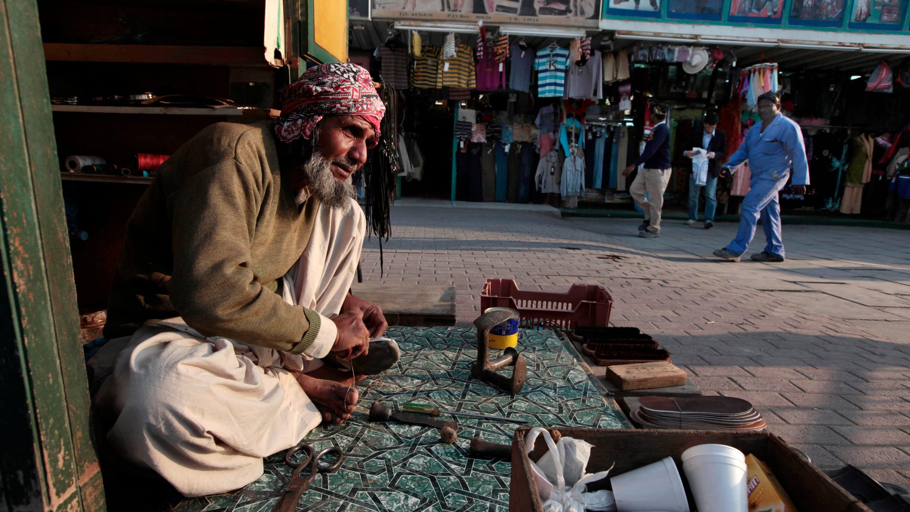FILE - In this Thursday, Jan. 20, 2011 file photo, a migrant worker repairs shoes at his stall in Doha, Qatar. Dozens of migrant workers hired to do construction work on a prominent skyscraper in Qatar are running low on food after working for almost a year without pay, a leading rights group said on Wednesday, Dec. 18, 2013. (AP Photo/Saurabh Das, File)