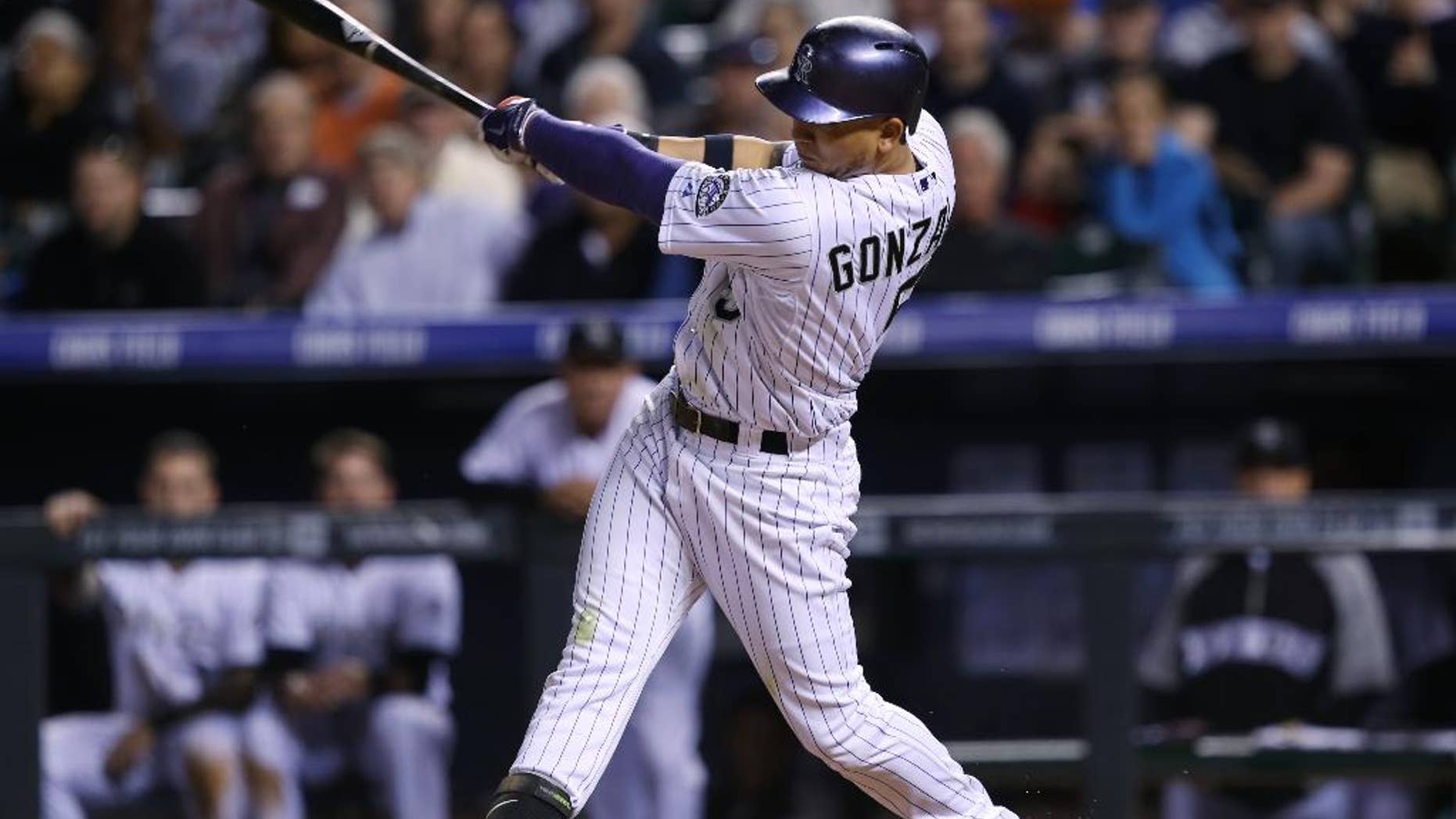 Colorado Rockies' Carlos Gonzalez follows through with his swing after connecting for an RBI-single against the Texas Rangers in the sixth inning of an interleague baseball game in Denver on Tuesday, May 6, 2014. (AP Photo/David Zalubowski)