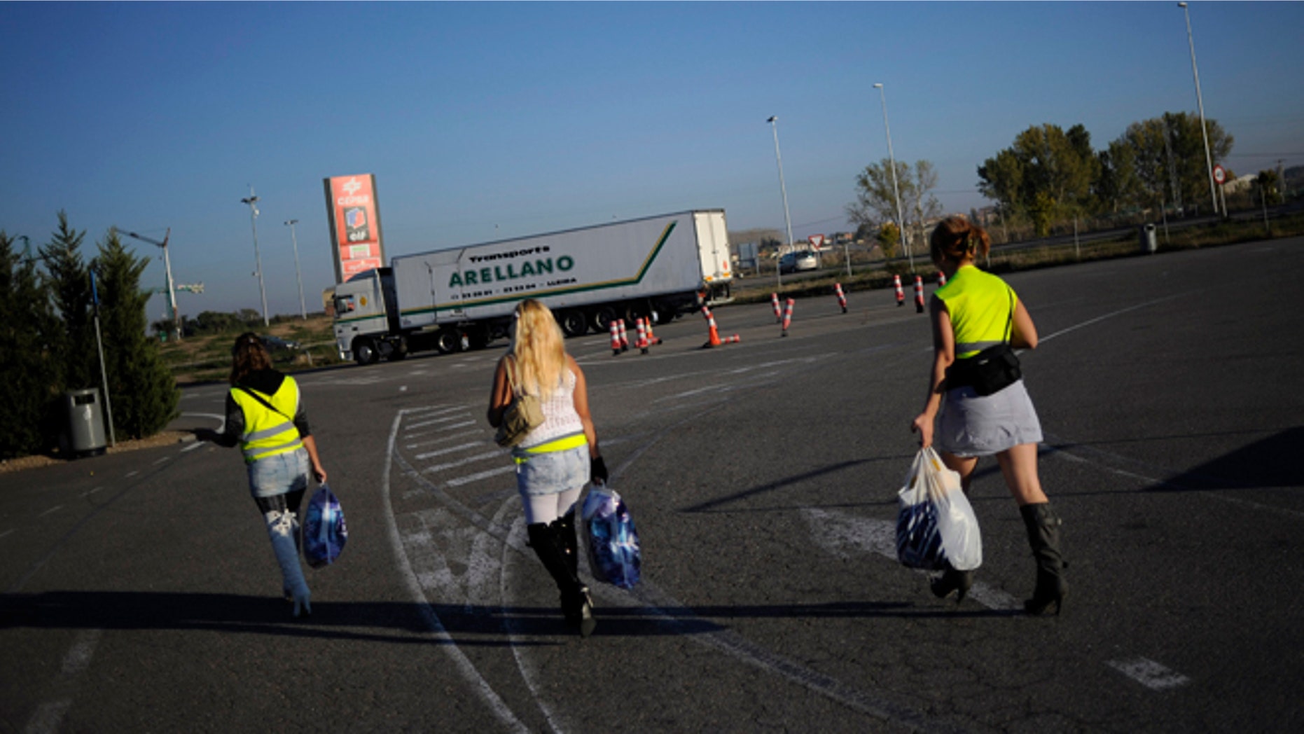 LLEIDA, SPAIN - OCTOBER 28: Three prostitutes wear reflective vests as they walk along a road on October 28, 2010 near Els Alamus in Lleida, Spain. Prostitutes working near a highway roundabout near Els Alamus have this month started to wear the reflective jackets to avoid fines of 40 Euros following a police crackdown. (Photo by David Ramos/Getty Images)