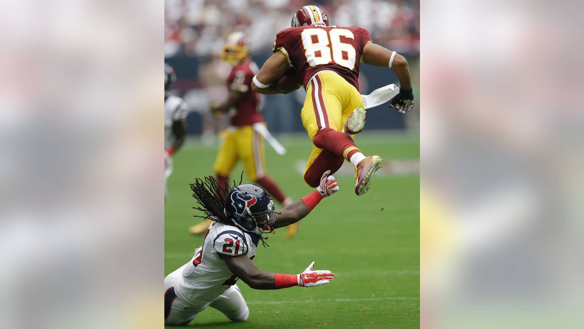 Houston Texans' Kendrick Lewis (21) trips up Washington Redskins' Jordan Reed (86) during the first quarter of an NFL football game Sunday, Sept. 7, 2014, in Houston. (AP Photo/David J. Phillip)