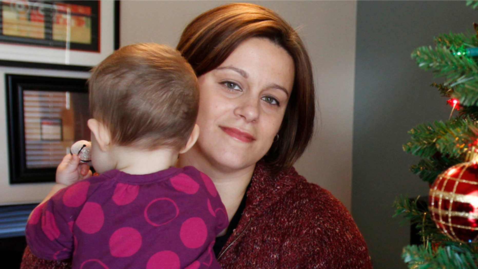 FILE - This photo made Dec. 8, 2011, in Withamsville, Ohio, shows teacher Christa Dias holding her 11-month-old daughter in her home. (AP Photo/The Cincinnati Enquirer, Gary Landers, File)