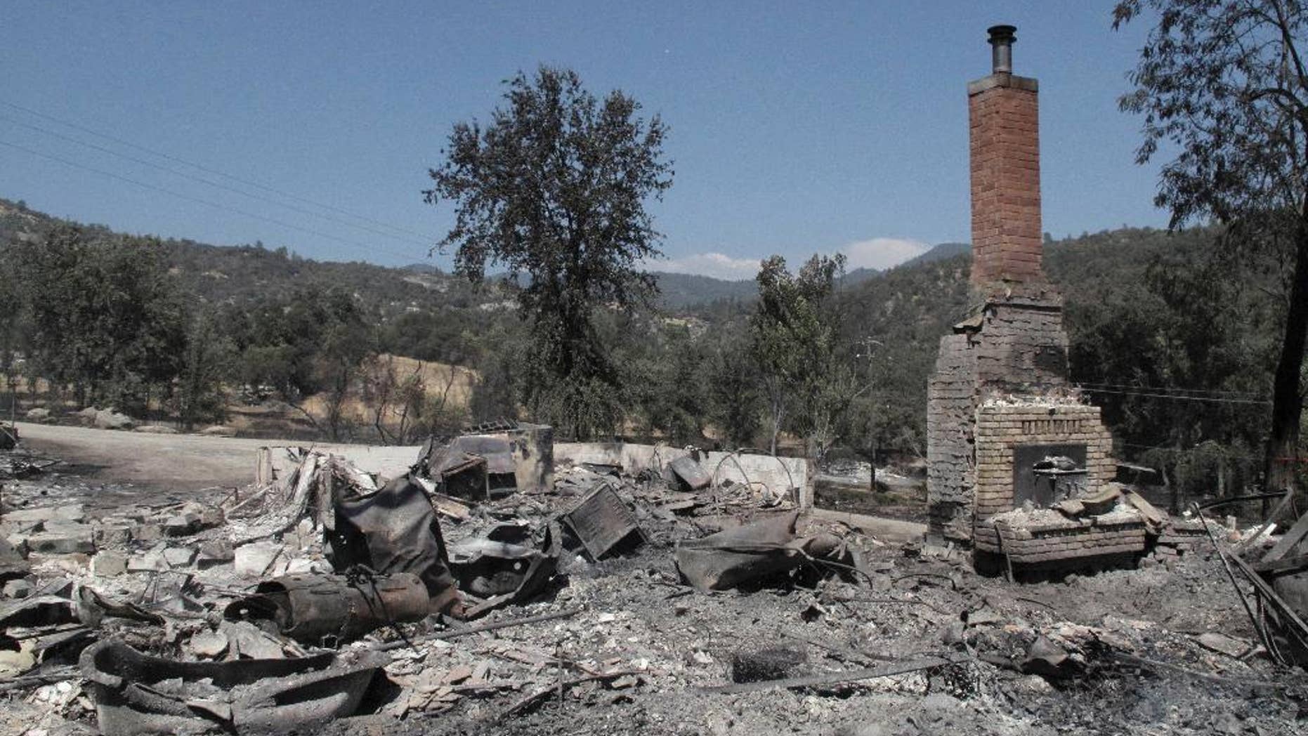 A chimney stands amid the remains of a burnt structure near Oakhurst, Calif., on Tuesday, Aug. 19, 2014. A wildfire that forced about 1,000 people from their homes in the foothills near Yosemite National Park held steady Tuesday as humidity and calmer winds aided the fight against the second blaze around the park in recent weeks. (AP Photo/Scott Smith)