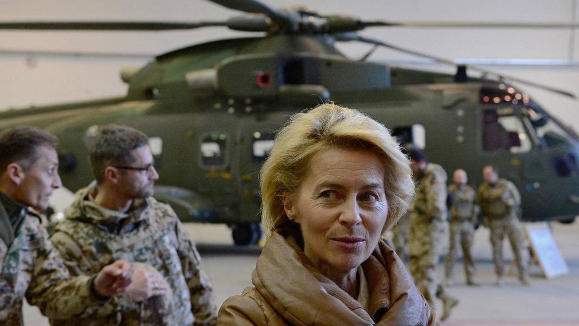 FILE - In this Dec. 13, 2014 file picture German Defense Minister Ursula von der Leyen, center, greets German helicopter pilots in a hangar at Camp Marmal in Mazar-i-Sharif, Afghanistan. Germany is affirming its growing role on the world stage in new security guidelines that mark another step away from its caution after World War II. A draft defense policy paper obtained by The Associated Press Tuesday July 12, 2016 and due to be presented on Wednesday states that "Germany is a globally highly connected country ... which has a responsibility to actively shape the global order." (John MacDougall, Pool Photo via AP, file)