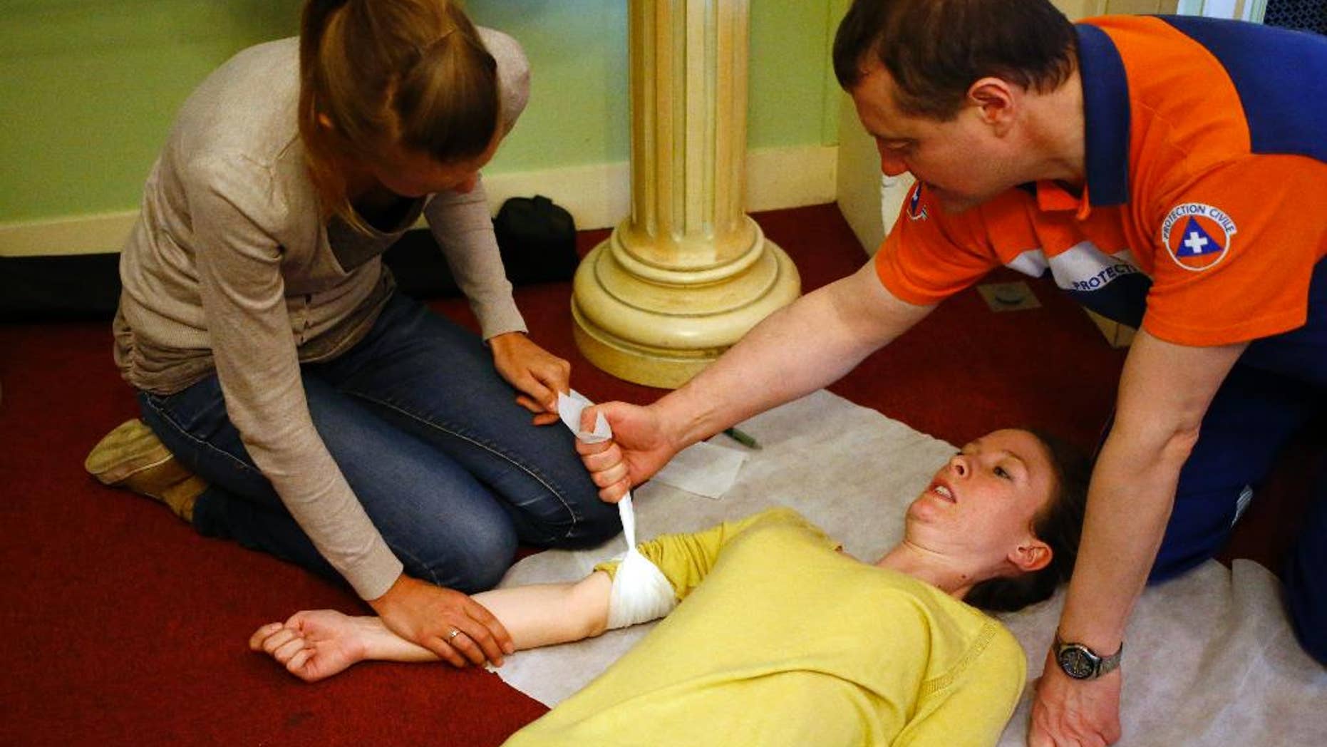 French Protection Civile rescuer Philippe Aubertin, right, attends free first aid training with Parisians in the French capital to be better prepared for future terror attacks, in Paris, France, Saturday, March 26, 2016. The two-hour sessions provided Saturday by rescuers in every district of Paris aim at teaching participants aged from 12 how to react in emergency situations. (AP Photo/Francois Mori)