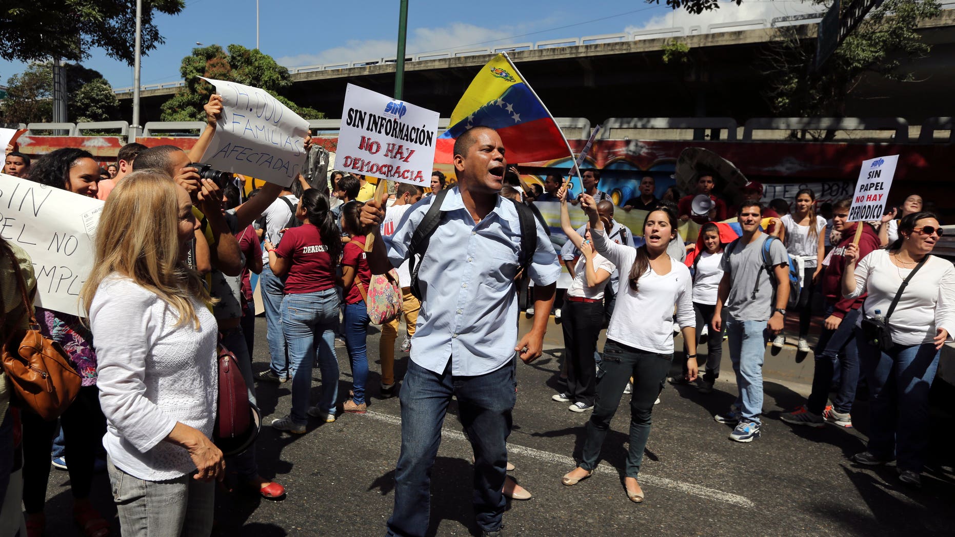 Un empleado del diario El Nacional sostiene un cartel que dice "sin información no hay democracia" durante una protesta afuera del Centro Nacional de Comercio Exterior, organismo oficial encargado de otorgar los permisos para vender dólares en Caracas, Venezuela, el 28 de Enero de 2014. Mientras que decenas de periódicos han sido víctimas de una política cambiaria que dificulta la importación de insumos, El Nacional está luchando para poder importar papel en medio de una creciente escasez del insumo que obligaría a muchas publicaciones a cerrar sus operaciones en las próximas semanas pues las reservas de papel han caído a su punto más bajo. (AP Foto/Fernando Llano)
An employee of El Nacional newspaper holds up a sign that reads in Spanish "Without information, there is no democracy", during a protest outside the Cadivi agency, which controls foreign currency in Caracas, Venezuela, Tuesday, Jan. 28, 2014. While newspapers have been beset for years by currency controls that make it difficult to import supplies, El Nacional is scrambling for newsprint as worsening shortages threaten to take several publications out of circulation in the coming weeks as reserves of newsprint have fallen to an all-time low. (AP Photo/Fernando Llano)
