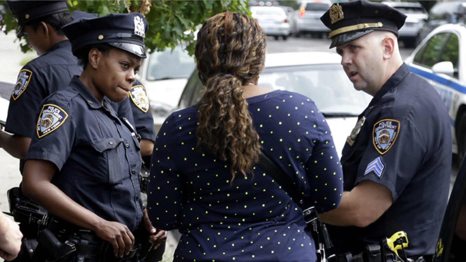 Police officers talk with a woman who had her phone stolen in the Brownsville section of Brooklyn, New York, Tuesday, Aug. 13, 2013. A federal judge's stinging rebuke of the police department's stop-and-frisk policy as discriminatory could usher in a return to the days of high violent crime rates and end New York's tenure as "America's safest big city," Mayor Michael Bloomberg warned. (AP Photo/Seth Wenig)