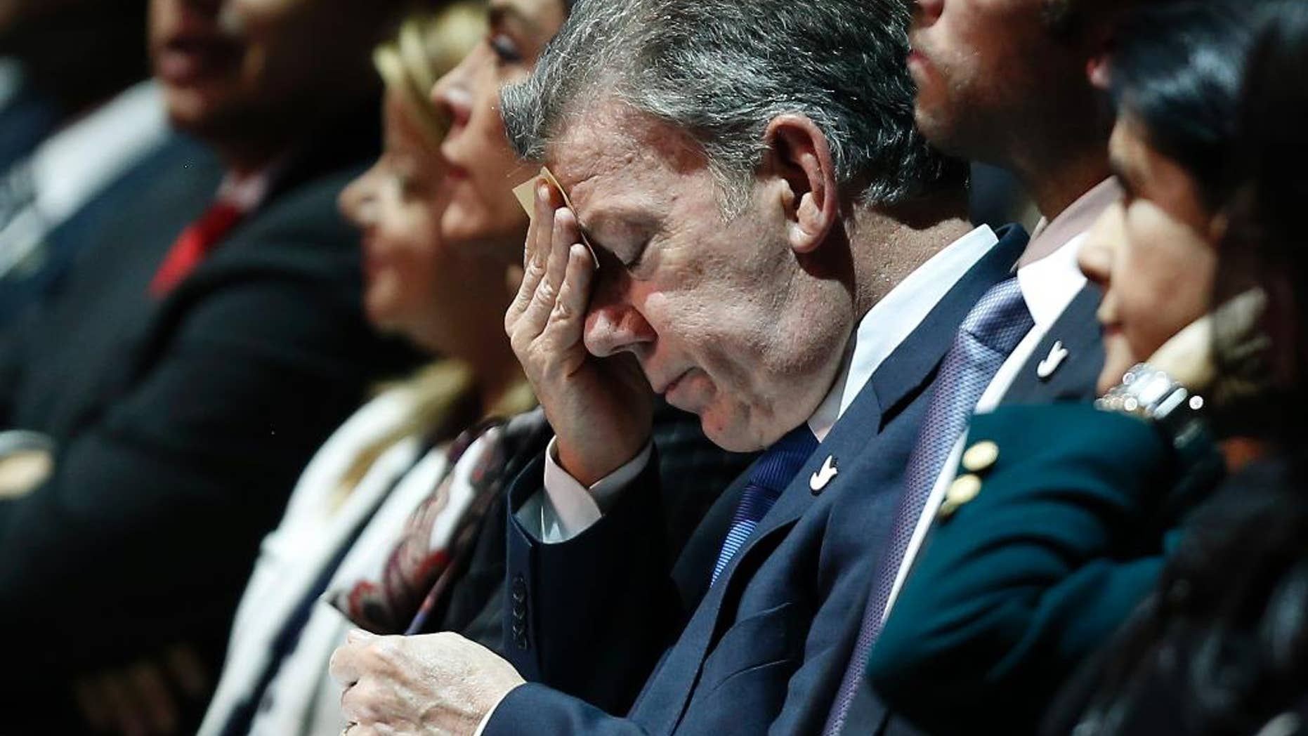 Colombia's President Juan Manuel Santos wipes his face as he listens to Vice President German Vargas Lleras present an annual report in Bogota, Colombia, Tuesday, March, 14, 2017. Earlier in a video message, Santos apologized to Colombians Tuesday after revelations that a scandal-tarred Brazilian construction company illegally paid costs related to his 2010 campaign. (AP Photo/Fernando Vergara)