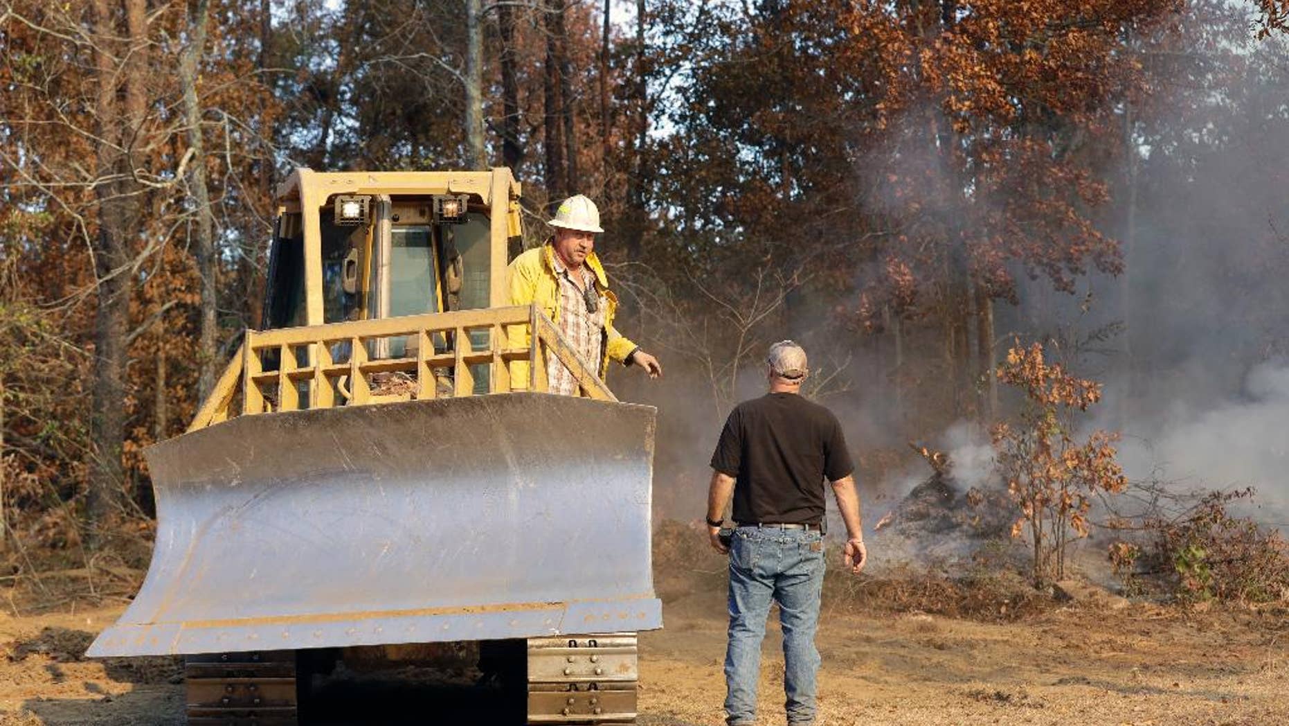 Bulldozer operator Jody McDonald, left, talks with Assistant Chief Dusten Woodard, right, of the Mowbray Volunteer Fire Depart, as McDonald cuts a firebreak to fight a wildfire Thursday, Nov. 10, 2016, in Soddy-Daisy, Tenn. Federal authorities say warmer-than-average temperatures and no rainfall are deepening a drought that's sparking forest fires across the Southeastern U.S. (AP Photo/Mark Humphrey)
