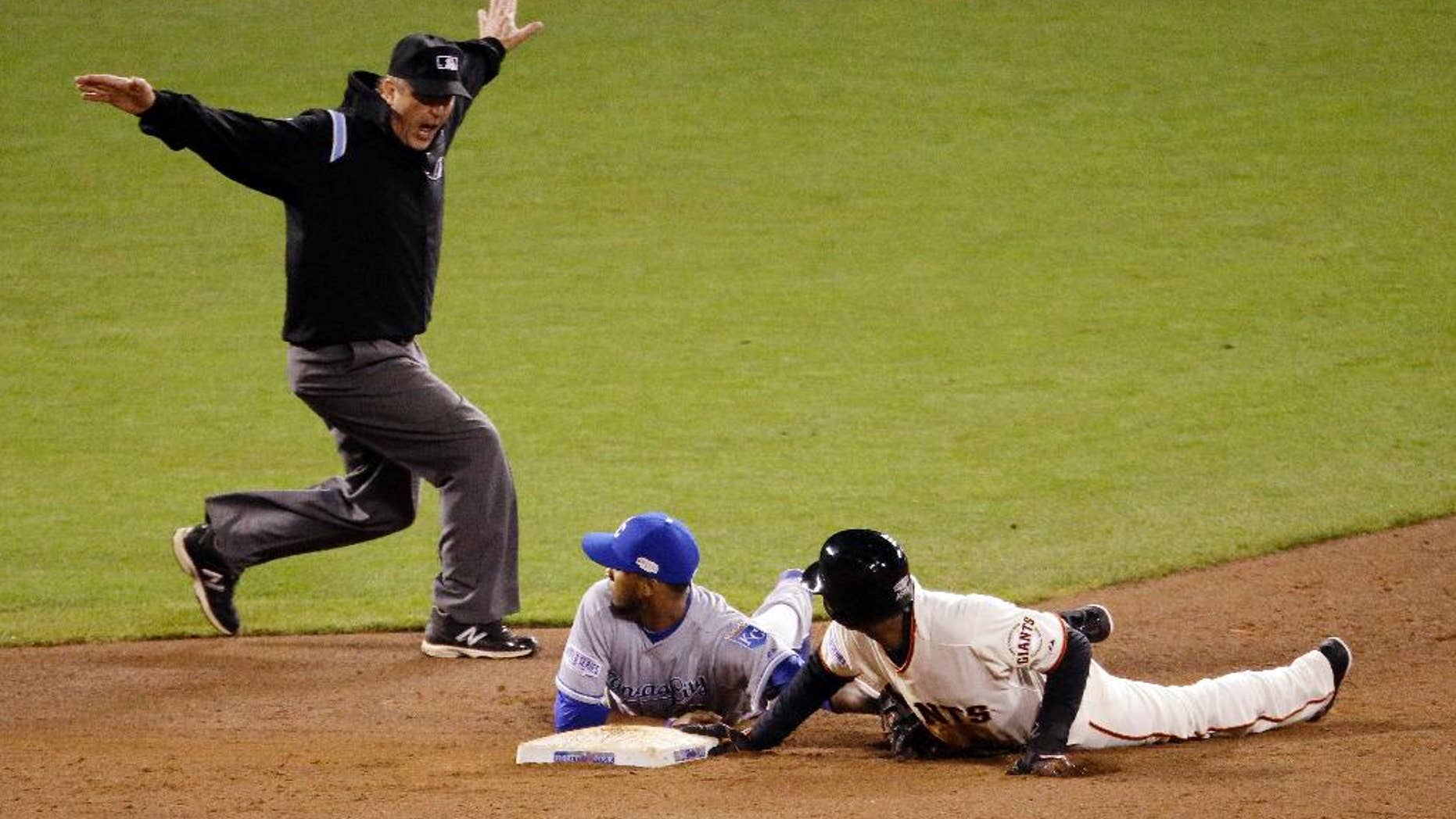 San Francisco Giants' Joaquin Arias is safe at second by umpire Jeff Nelson on a throw by Kansas City Royals' catcher Salvador Perez to Alcides Escobar, center, during the sixth inning of Game 4 of baseball's World Series Saturday, Oct. 25, 2014, in San Francisco. (AP Photo/Charlie Riedel)