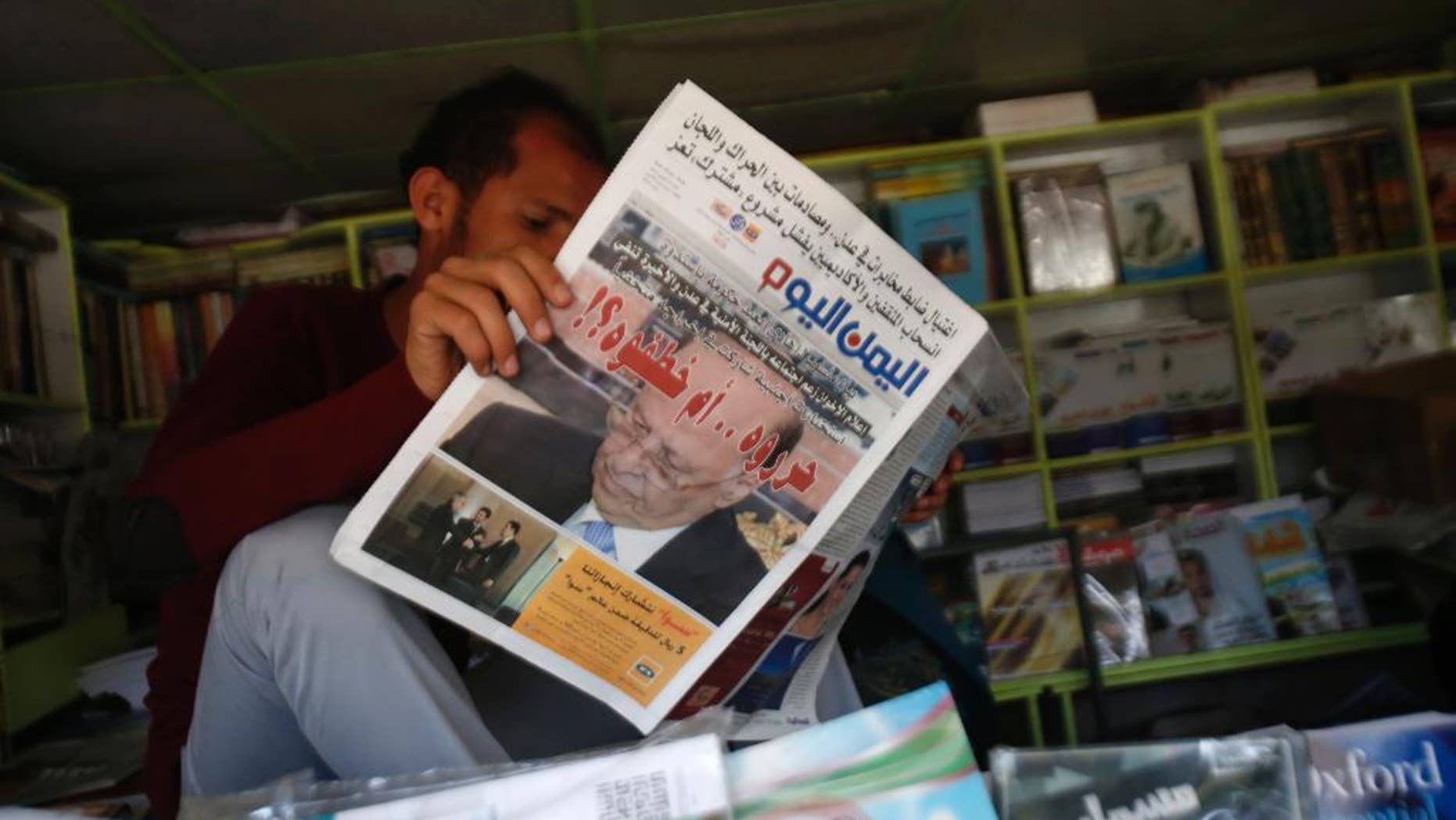 A Yemeni man reads a newspaper featuring the front page with a photograph of former President Abed Rabbo Mansour Hadi, and a headline in Arabic that reads, " did they release him or kidnap him?" in Sanaa, Yemen, Sunday, Feb. 22, 2015. Virtually powerless for months, Yemen’s overthrown President Hadi appeared ready to disappear from the country after fleeing Shiite rebels who held him captive in his own home. But the soft-spoken technocrat who long has avoided the limelight stepped back into it Saturday by renouncing his own resignation and challenging the Shiite Houthi rebels who hold control the capital and large parts of the country. (AP Photo/Hani Mohammed)